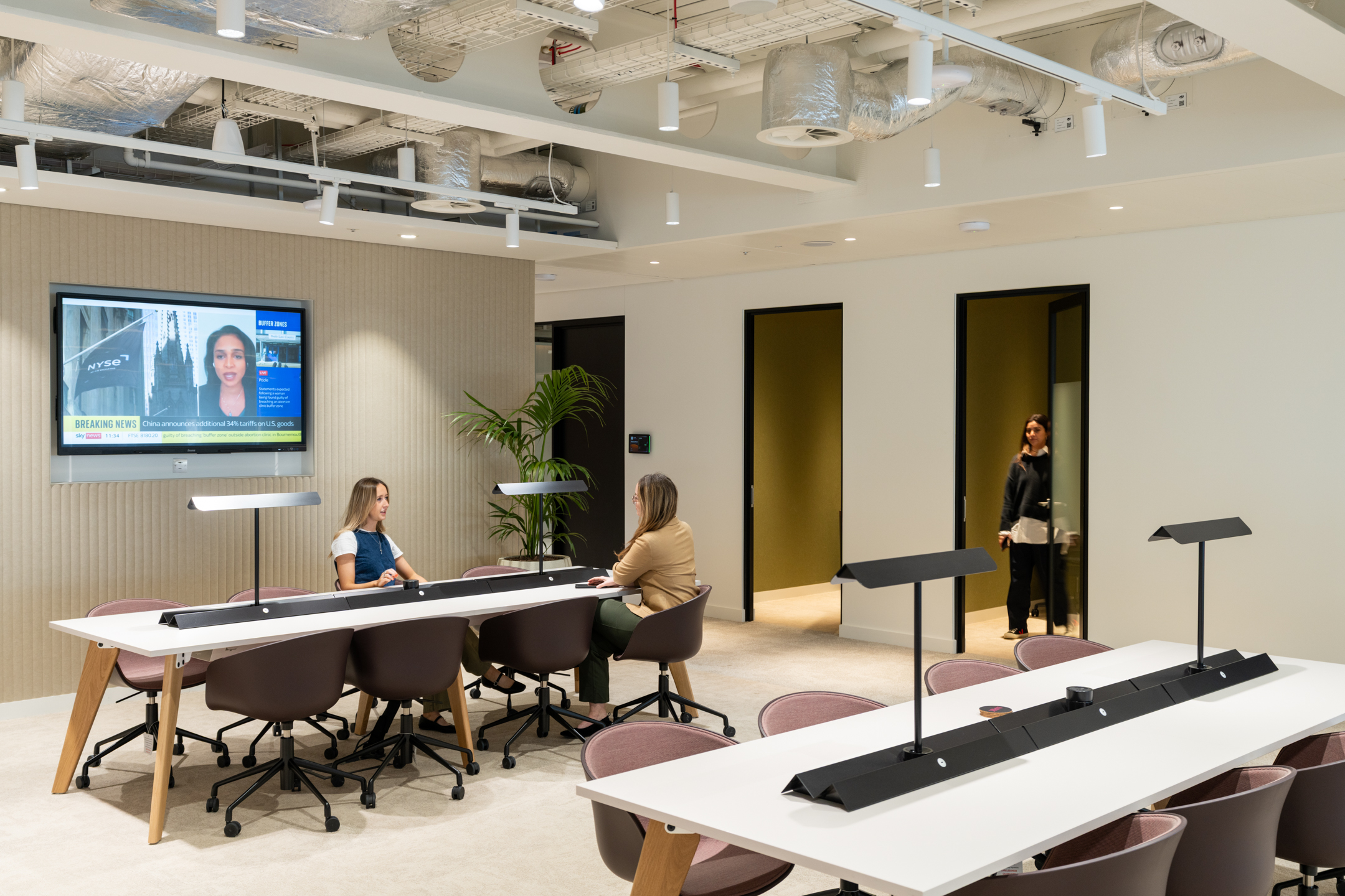 Ark Syndicate open-plan workbench with swivel chairs and sleek desk lights designed for quiet focus and flexible teamwork.