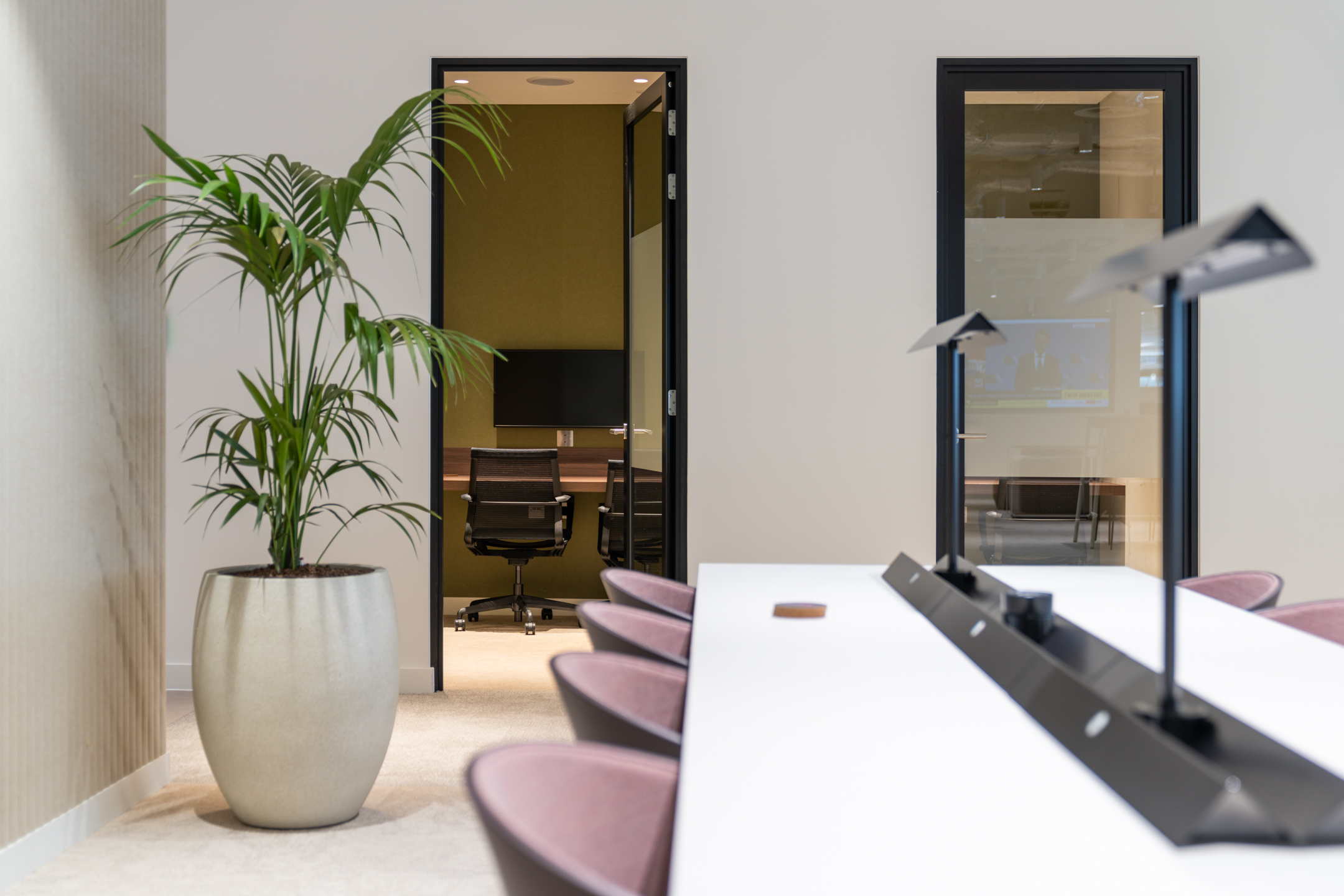 Ark Syndicate quiet zone with open booths, desk lighting and greenery designed to support solo work with a touch of calm focus.