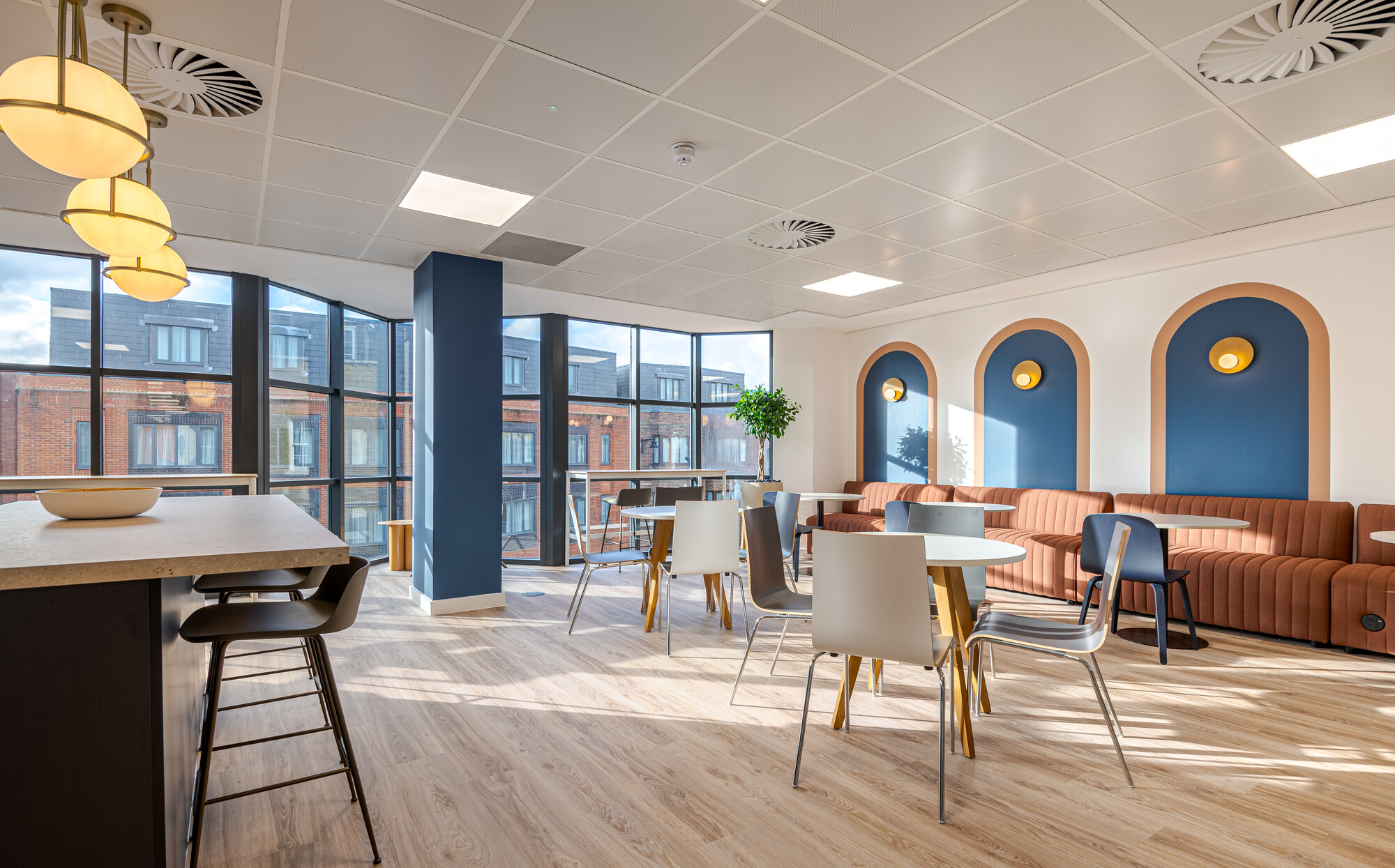 Sunlit teapoint at Accelya with layered booth seating, globe lighting and curved detailing, styled by Platfform with aviation-inspired flair.