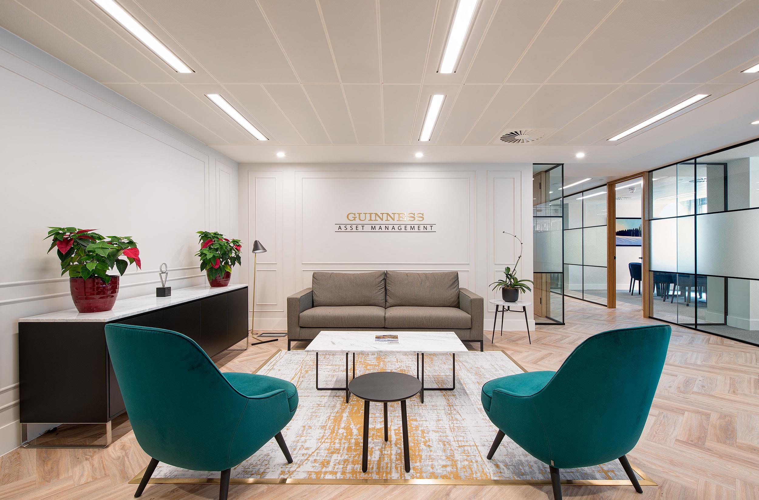 Reception seating area at Guinness Asset Management featuring furniture supplied by Platfform, including teal lounge chairs, a neutral-toned sofa, and minimalist tables.