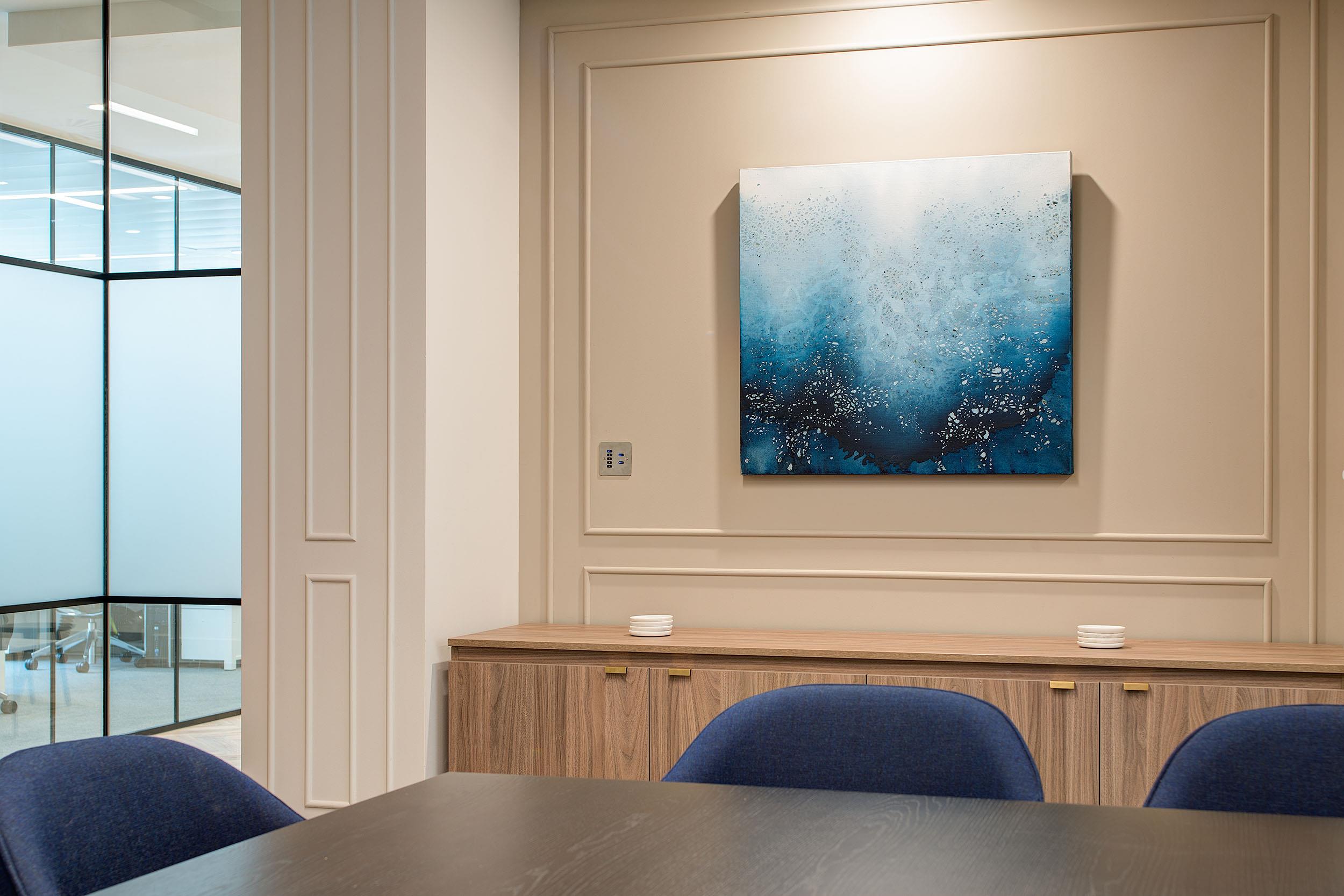 Meeting room detail at Guinness Asset Management, with Platfform-supplied navy chairs and wood credenza beneath abstract artwork in blue tones.