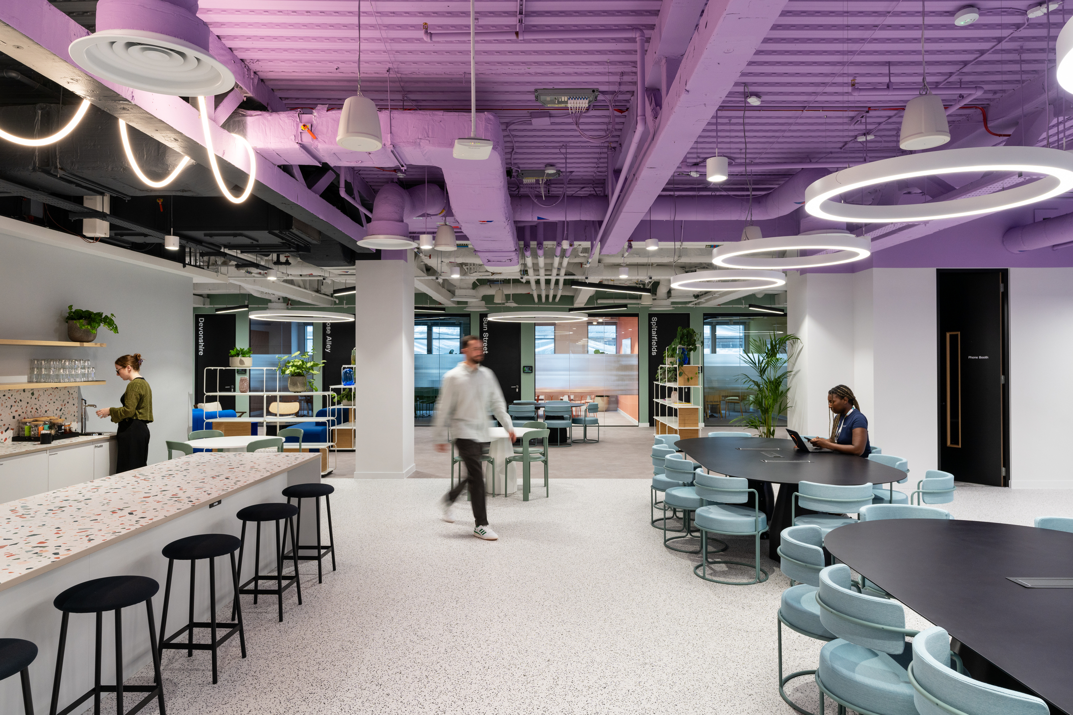 Open-plan coworking space at Huckletree, Bishopsgate, featuring terrazzo worktops, soft blue seating and standout lilac ceiling detail across the breakout zone.
