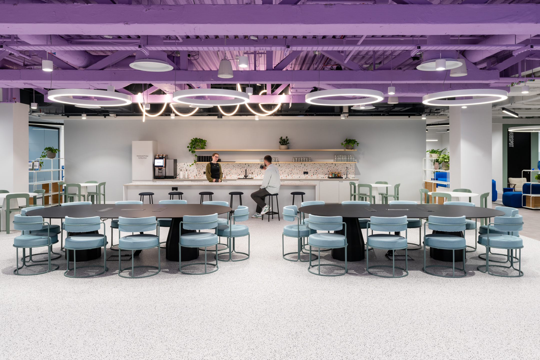 Teapoint at Huckletree, Bishopsgate, with terrazzo splashbacks, pastel green bar stools and soft blue meeting chairs beneath a bold lilac ceiling.