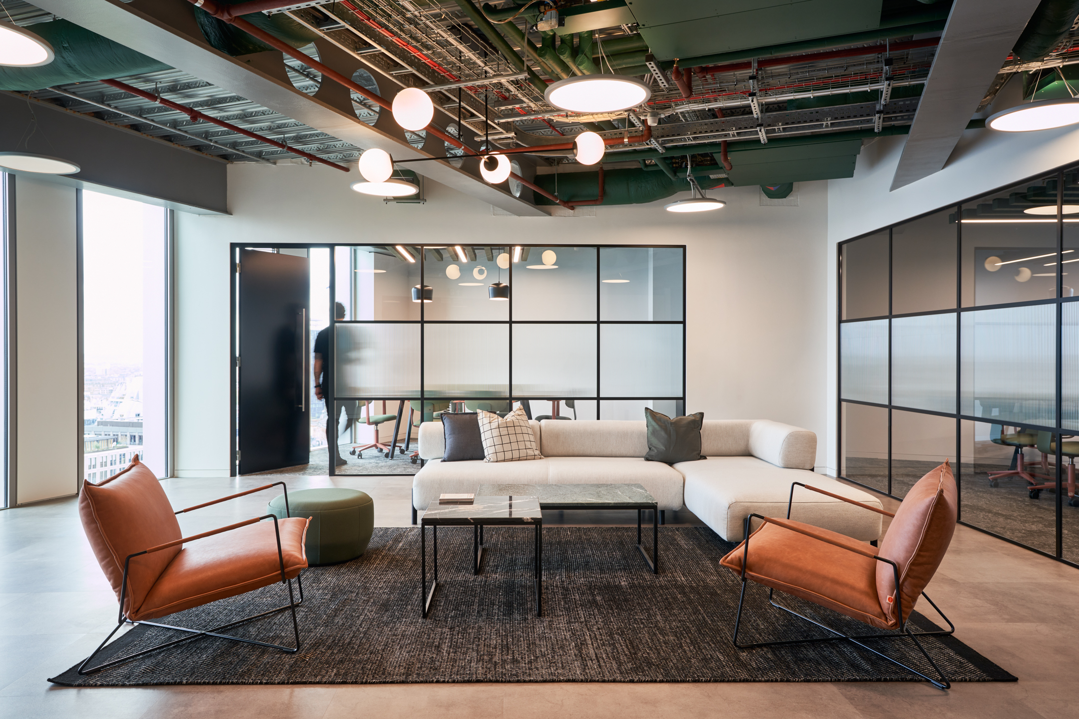 Modern lounge setting at HYLO with leather armchairs, a neutral corner sofa, and statement coffee tables, furnished by Platfform.