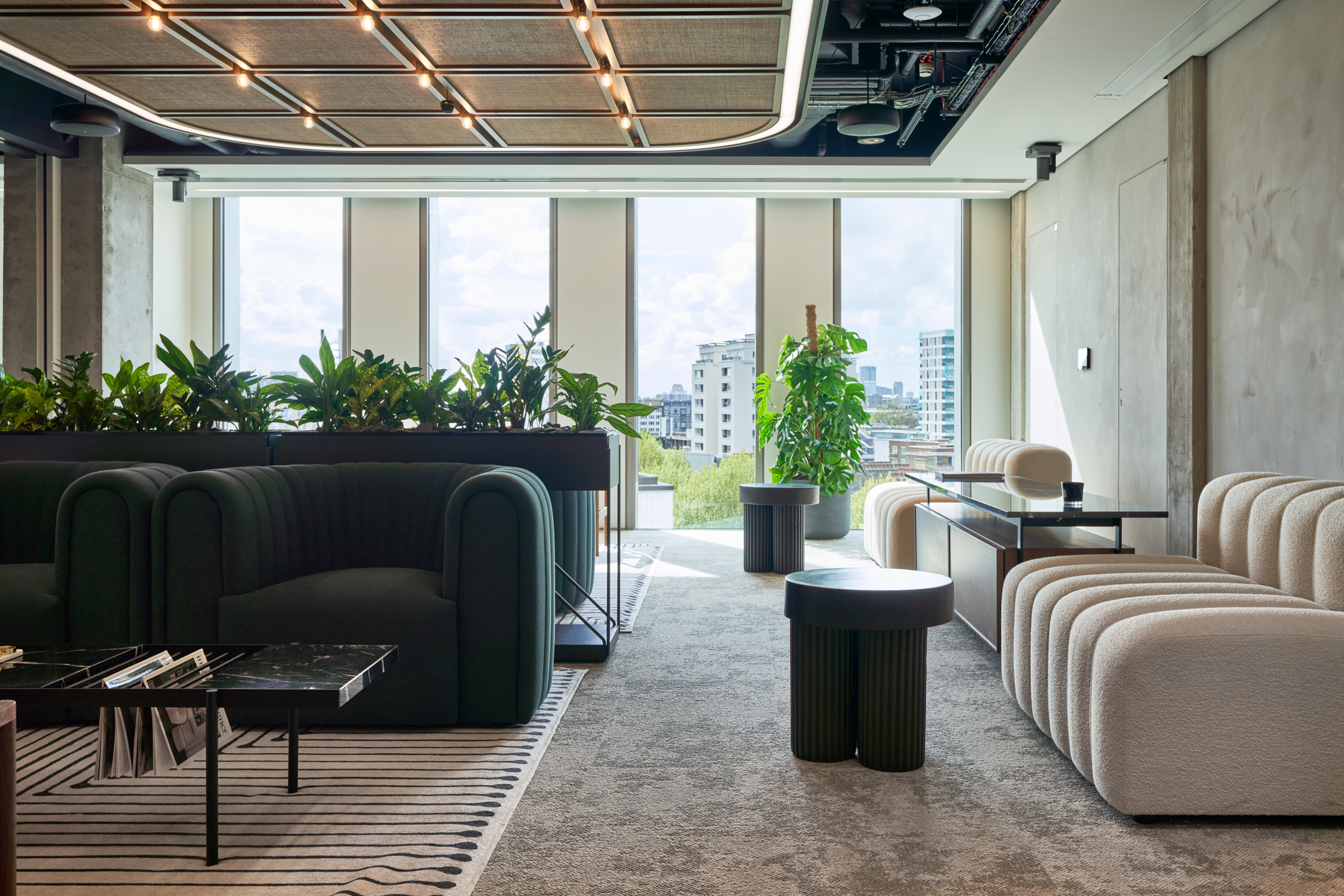 HYLO lounge space with boucle seating, deep green armchairs and sculptural side tables, with all furniture supplied by Platfform.