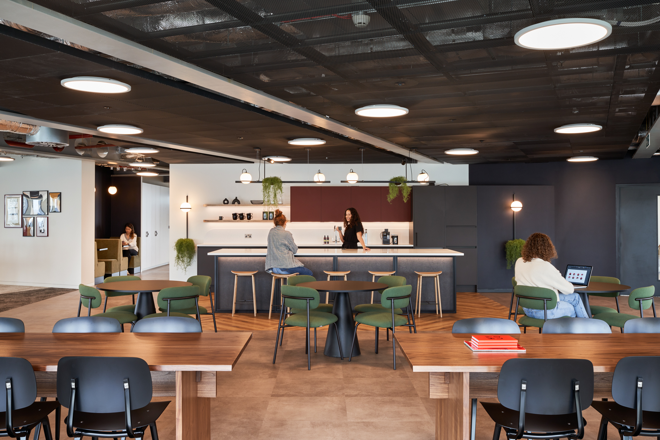 Multi-functional social hub at HYLO featuring green lounge chairs, timber tables and a central island, with furniture supplied by Platfform.