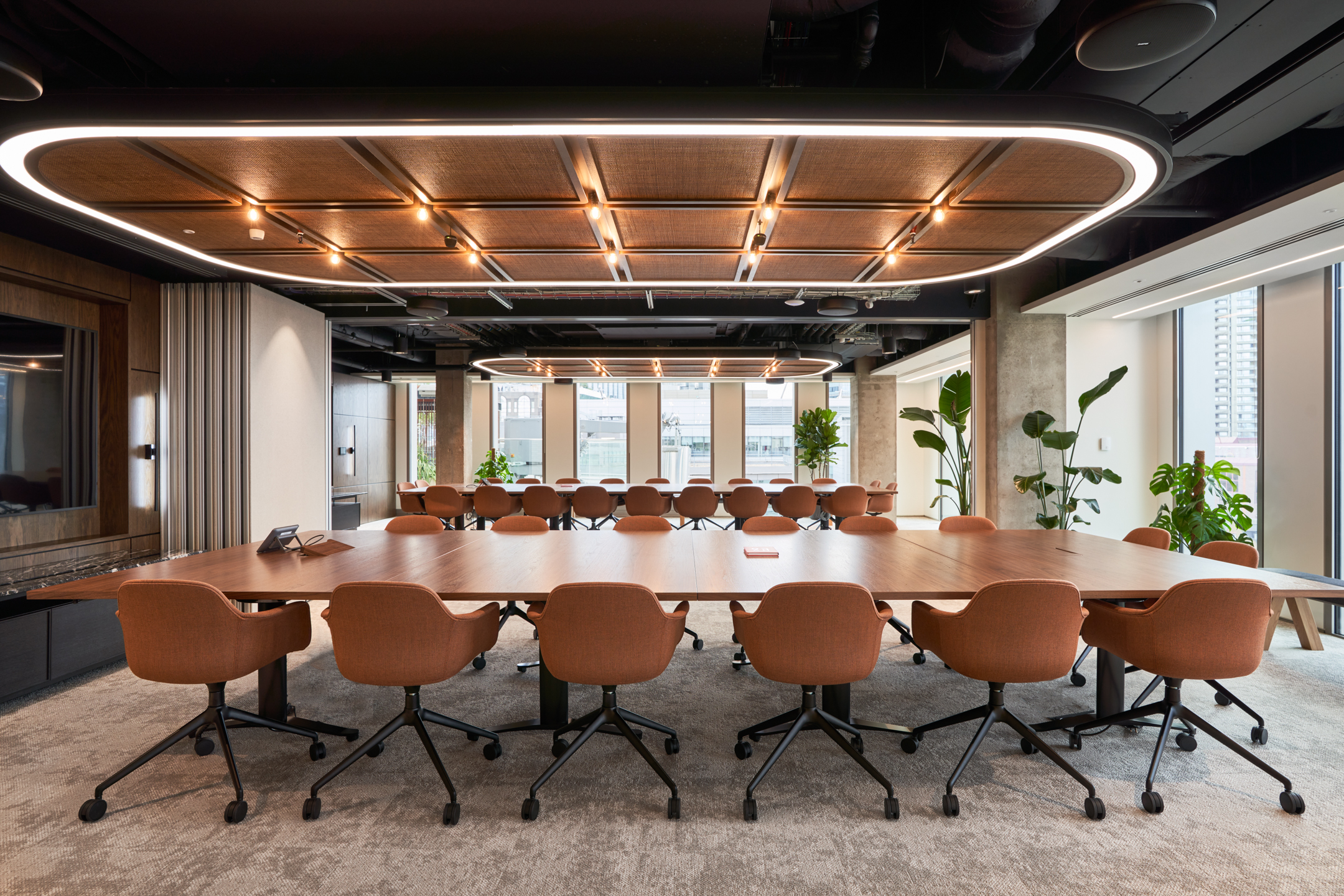 Large HYLO boardroom with rust-coloured meeting chairs and modular wood tables, with furniture curated and delivered by Platfform.