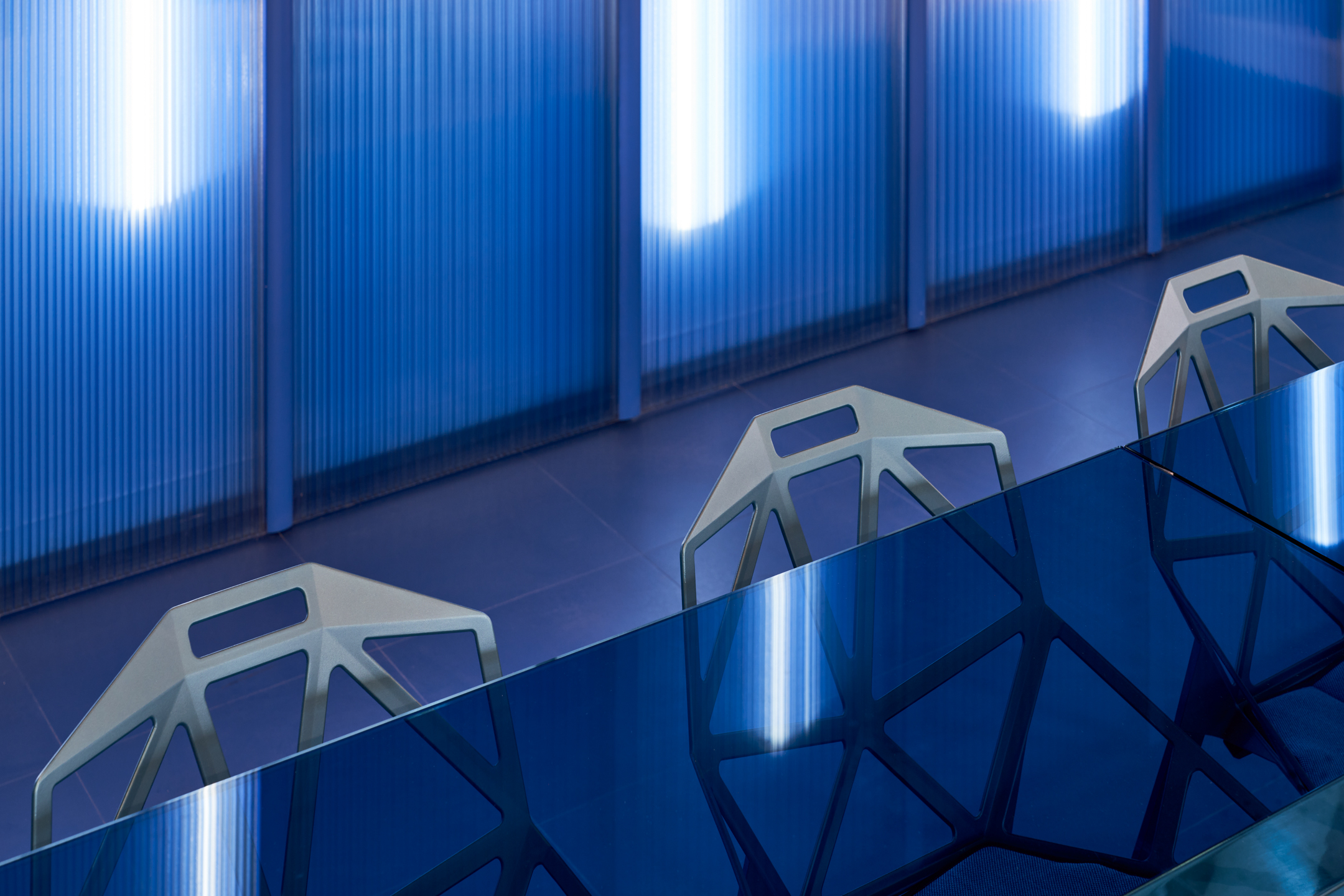 Close-up of angular meeting chairs and deep blue glass table at Huckletree Oxford Street, part of Platfform’s bold furniture package.