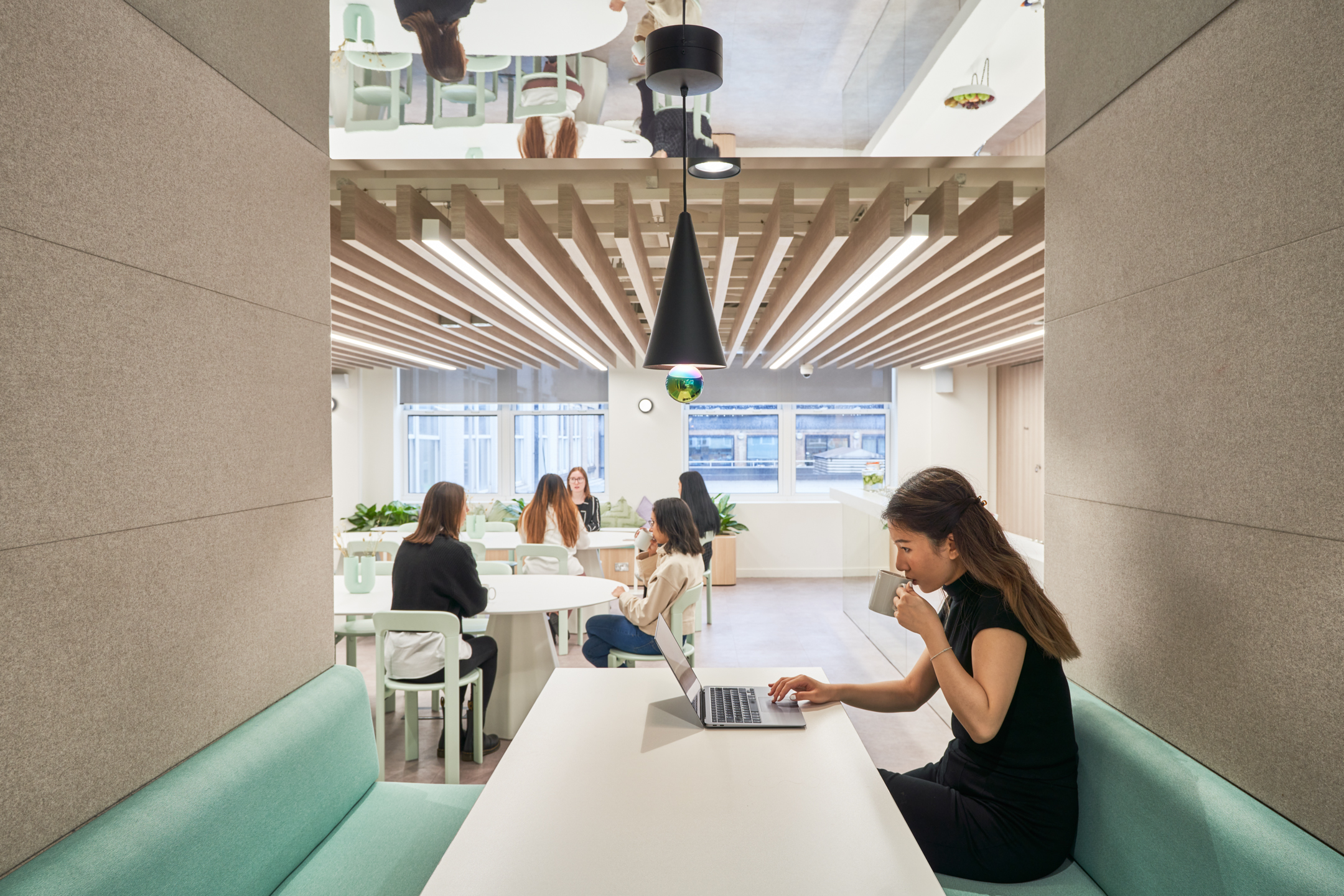 Collaborative workspace at Huckletree Oxford Street with mint green banquette seating and minimalist tables, furnished by Platfform.