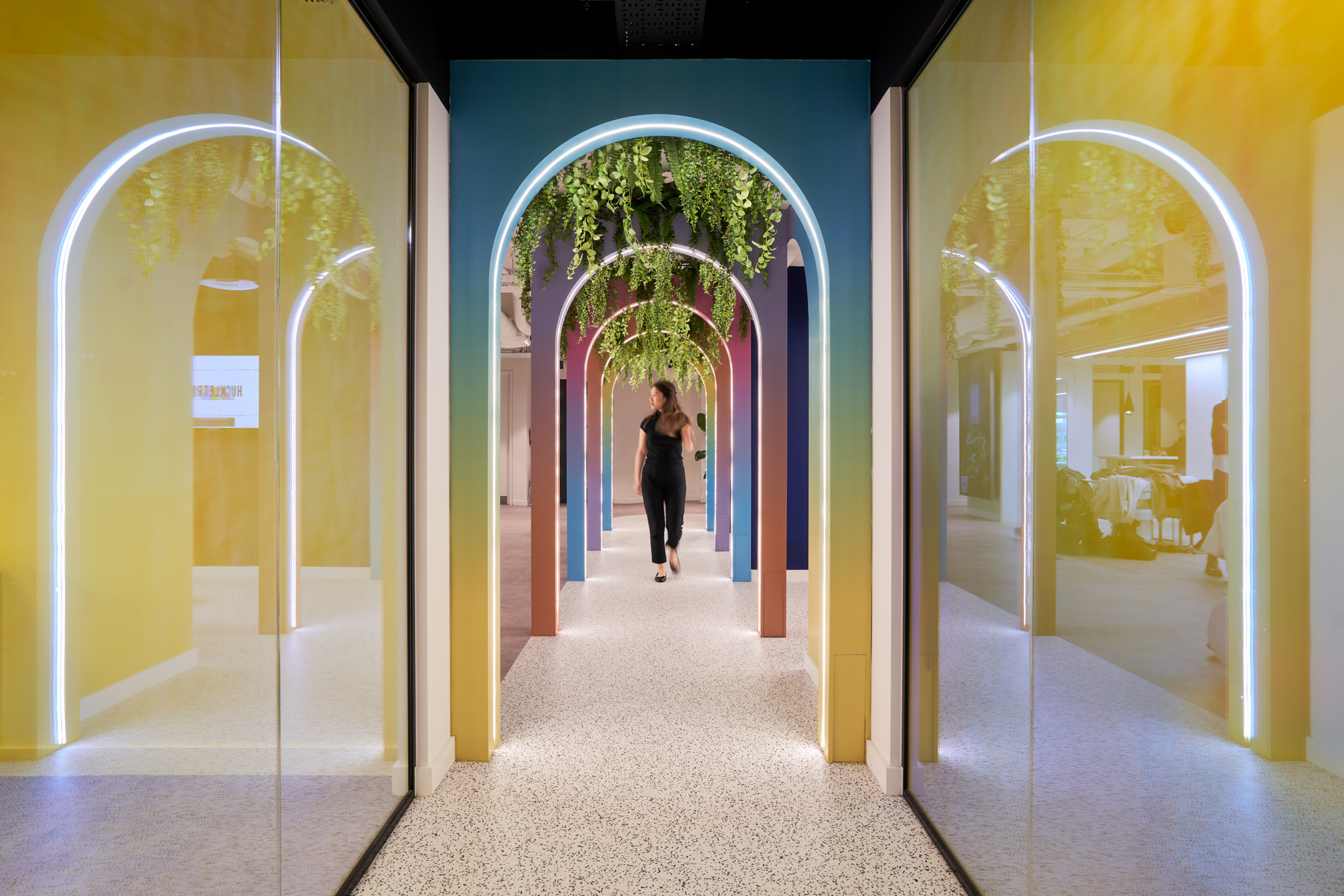 Statement archway corridor at Huckletree Oxford Street, designed with colour-fade panels and hanging greenery, leading into furnished zones by Platfform.