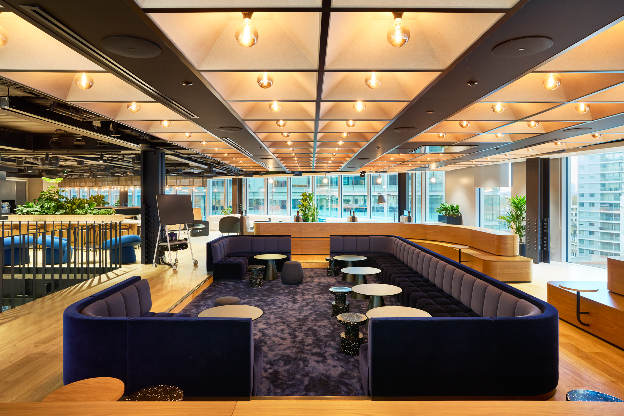 Agile breakout space at International Technology and Data Firm with deep blue modular seating, tiered steps and mobile furniture for team collaboration.