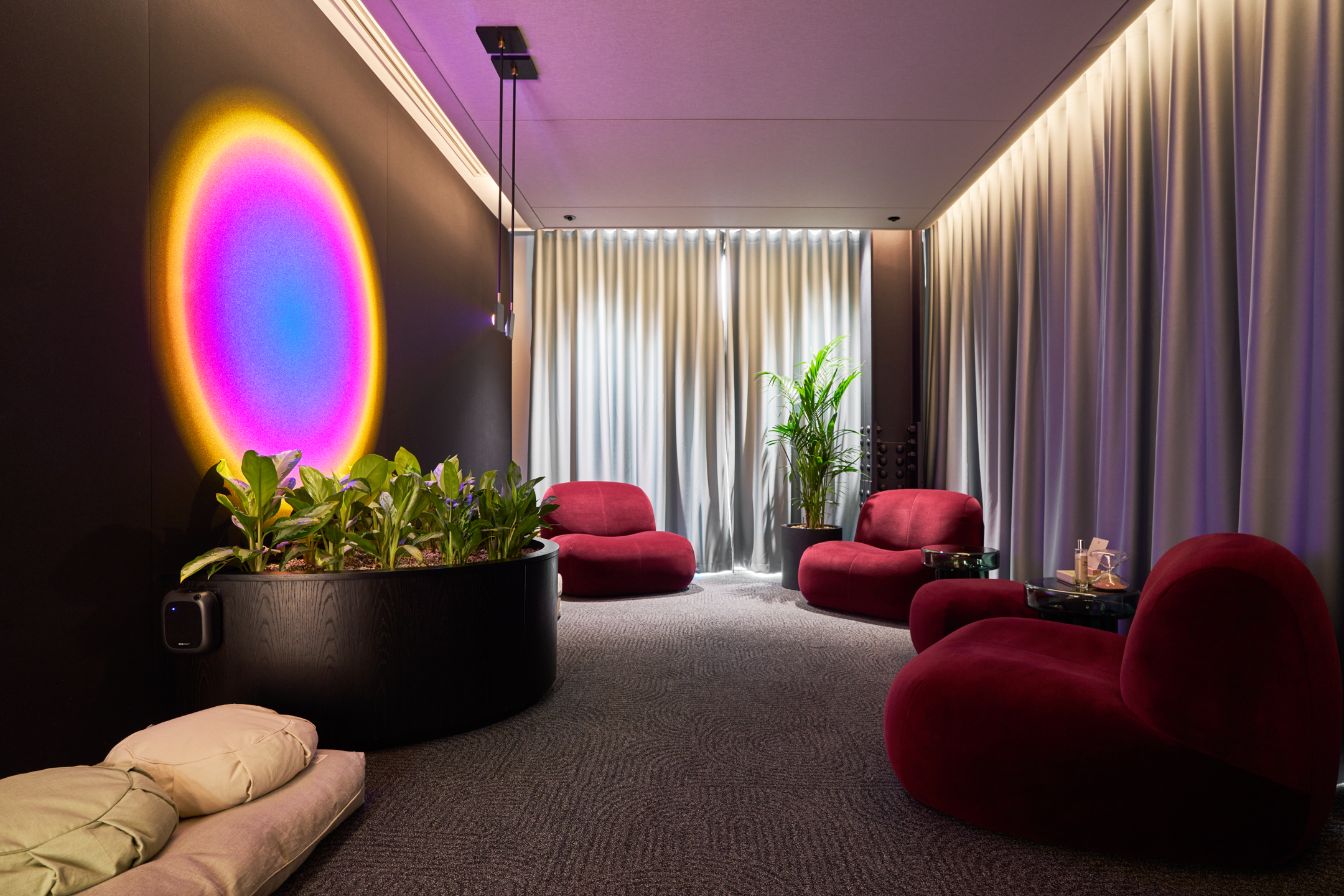 Meditation room at International Technology and Data Firm with soft red lounge seating, ambient lighting and biophilic accents for mindful retreat.