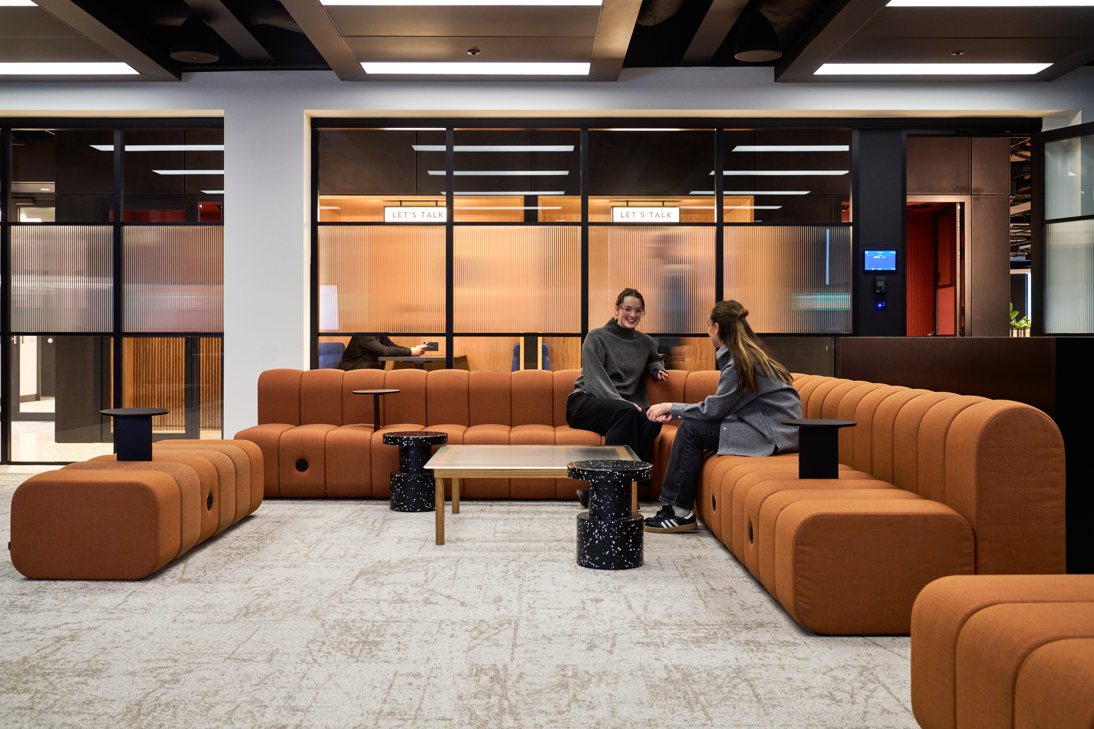 Breakout space at International Technology and Data Firm with terracotta modular seating and terrazzo tables, designed for informal conversation and downtime.