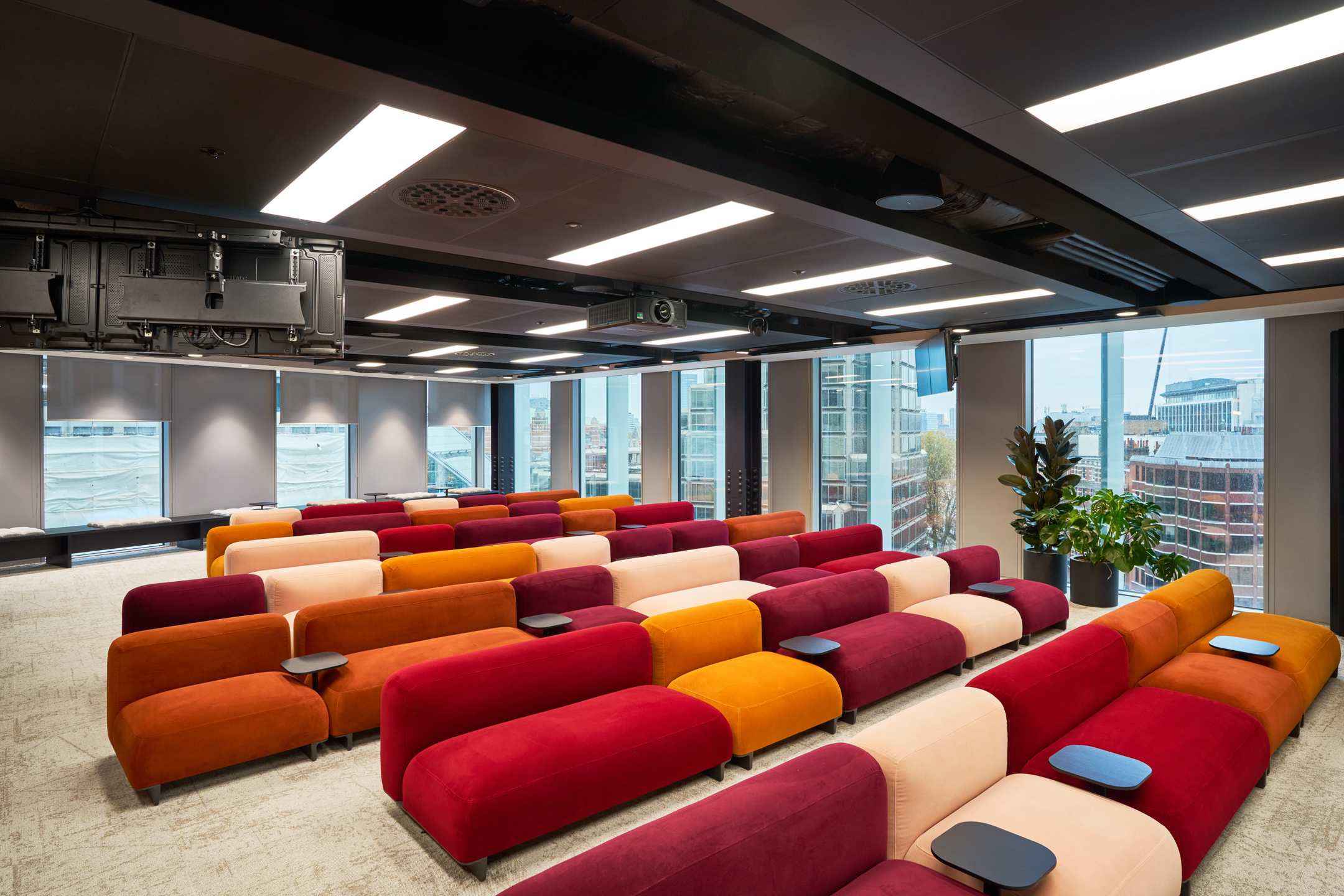Training room at International Technology and Data Firm with tiered modular seating in vibrant tones, built-in tables and panoramic city views.