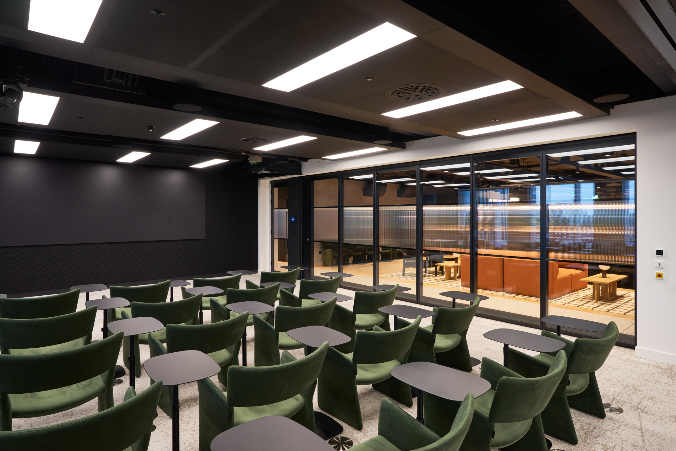 Flexible training room at International Technology and Data Firm with green chairs, folding glazed partitions and integrated tables for multi-use sessions.