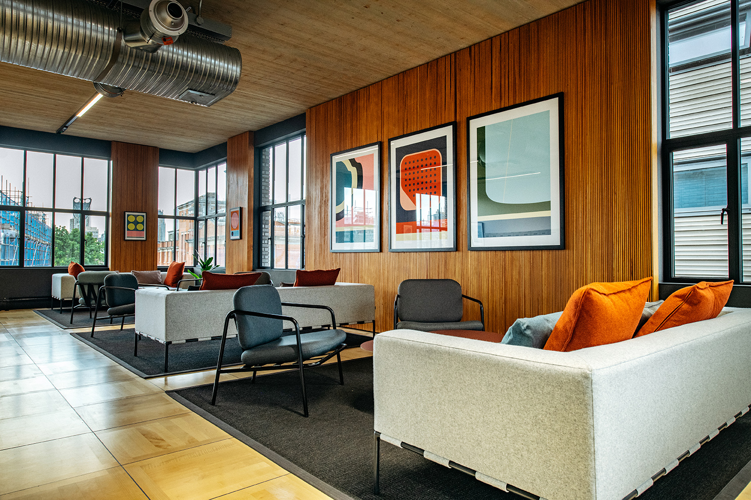 Light-filled breakout area at the Joseph Joseph office, with modern lounge seating, bold graphic artwork, and floor-to-ceiling windows.