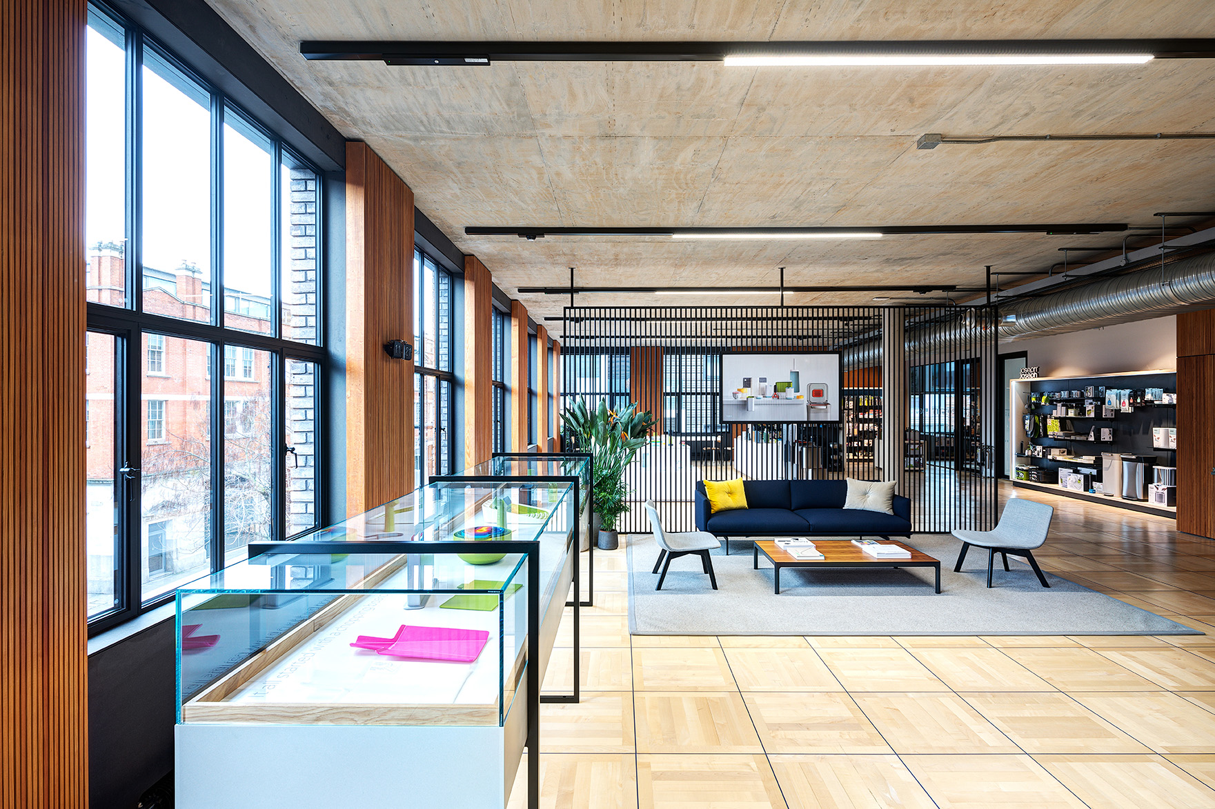 Reception area at the Joseph Joseph office with lounge seating and a product display zone showcasing colourful kitchenware under glass cabinets.