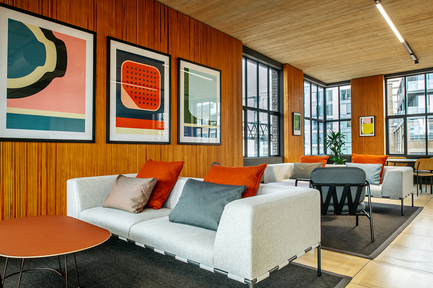 Breakout and collaboration area at the Joseph Joseph office, with soft seating, colourful artwork, and a warm timber-lined interior.