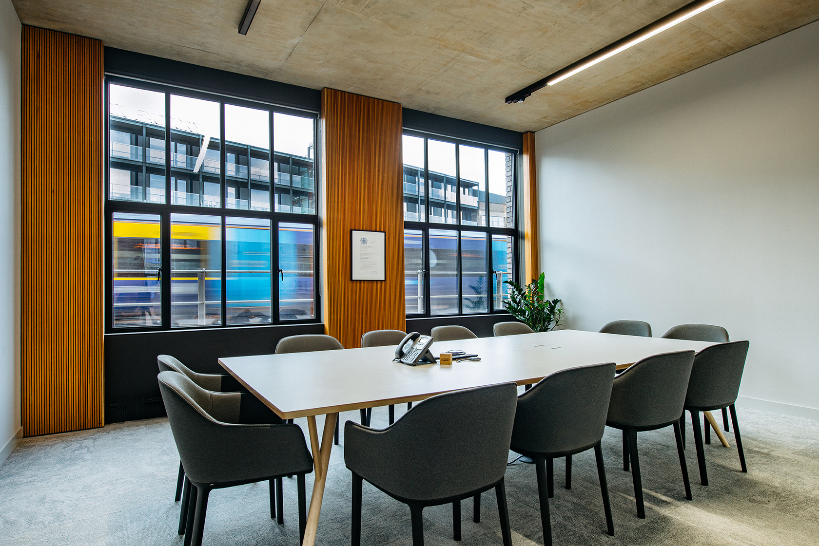 Meeting room at the Joseph Joseph office, featuring a minimalist conference table, upholstered chairs, and large windows with timber panelling.