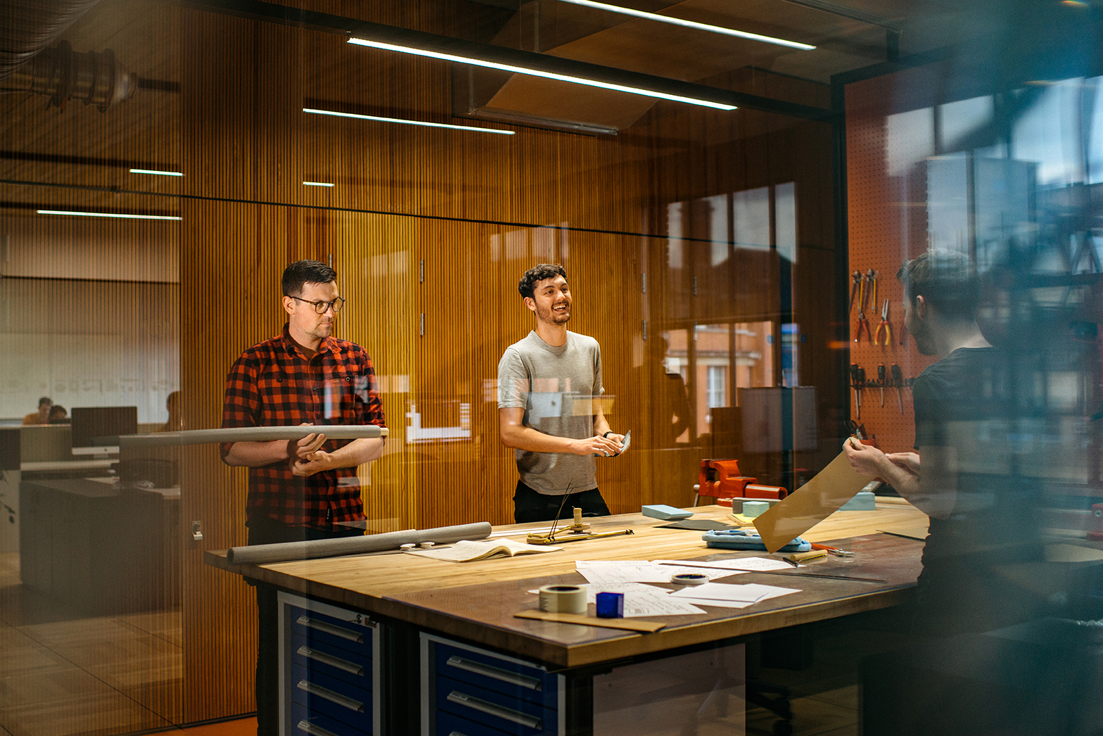 Workshop space at the Joseph Joseph office with timber walls, tools on display, and staff collaborating around a central workbench.