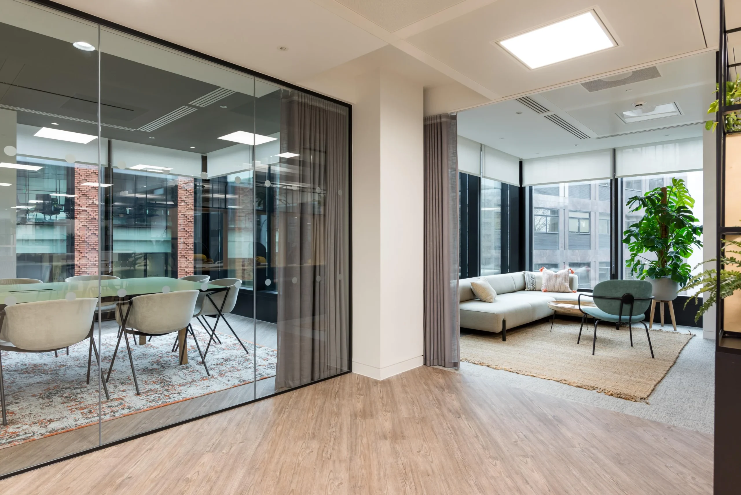 Breakout and meeting spaces furnished for London & Oriental, featuring a soft corner sofa and lounge chair beside floor-to-ceiling glazing, with a meeting room visible through glass partitions.