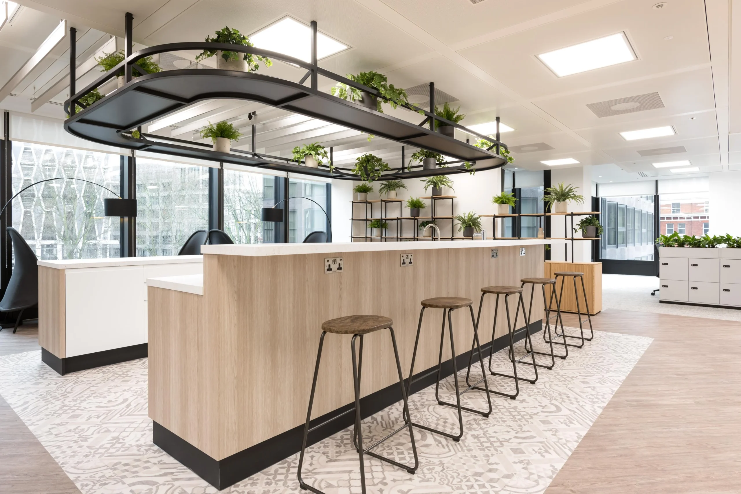 Bespoke furniture for London & Oriental including timber breakfast bar with metal stools, surrounded by integrated planting and contemporary workspace design.