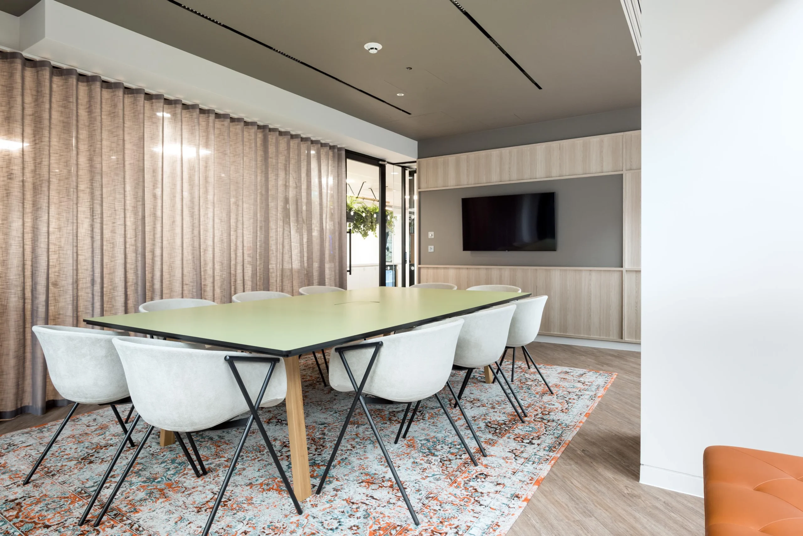 Meeting room furniture for London & Oriental, with a sage green table, upholstered chairs and a patterned rug adding texture to the calm, modern space.