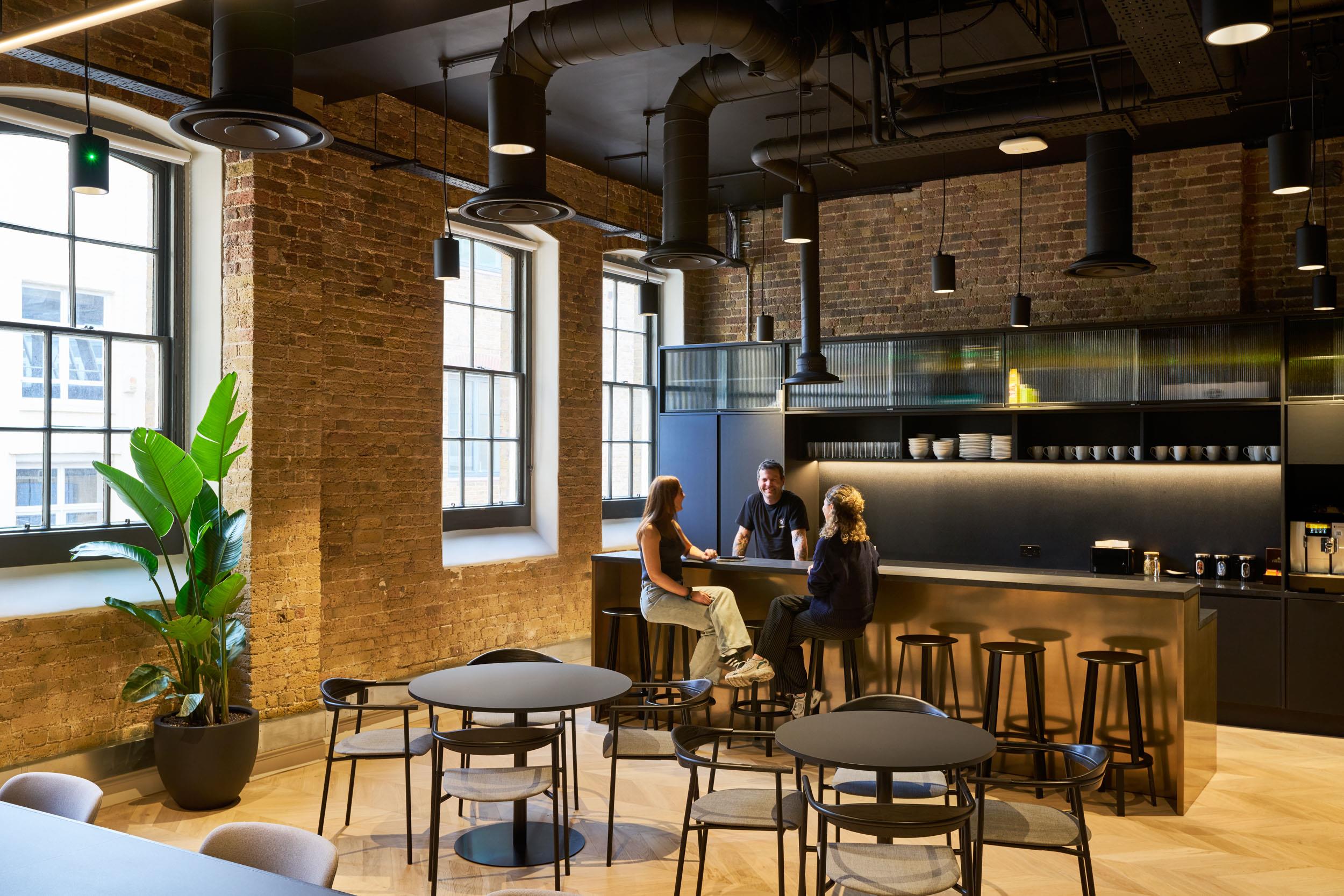 Teapoint and breakout furniture supplied for Lotus, including high stools and round dining tables within a relaxed brick-walled setting.