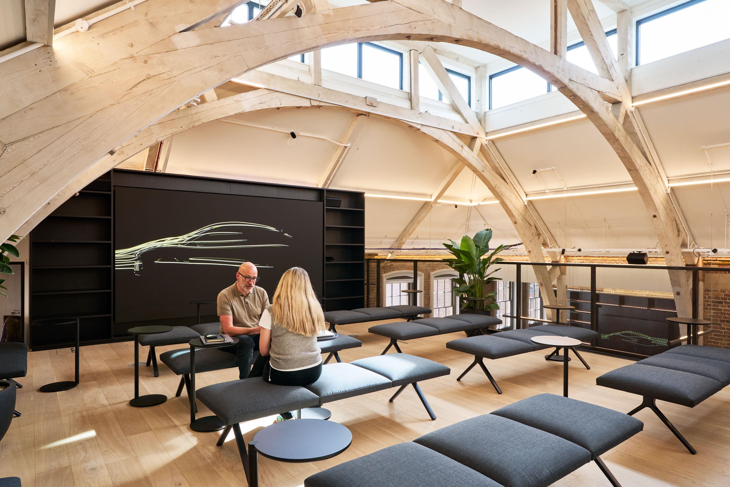 Tiered bench seating and side tables supplied for Lotus, arranged beneath vaulted timber beams in a mezzanine space with an integrated digital display.