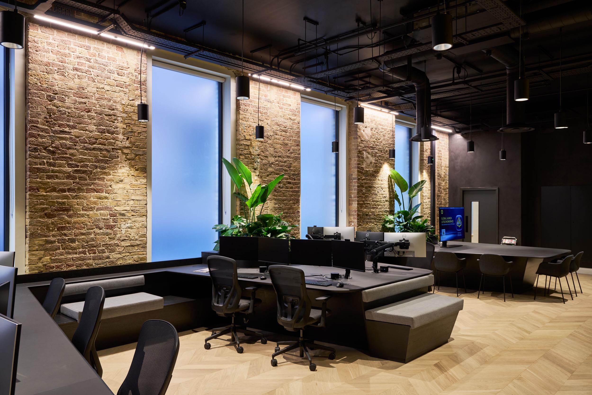 Custom workstations and integrated soft seating supplied for Lotus, designed around exposed brick walls and frosted windows with statement planting.