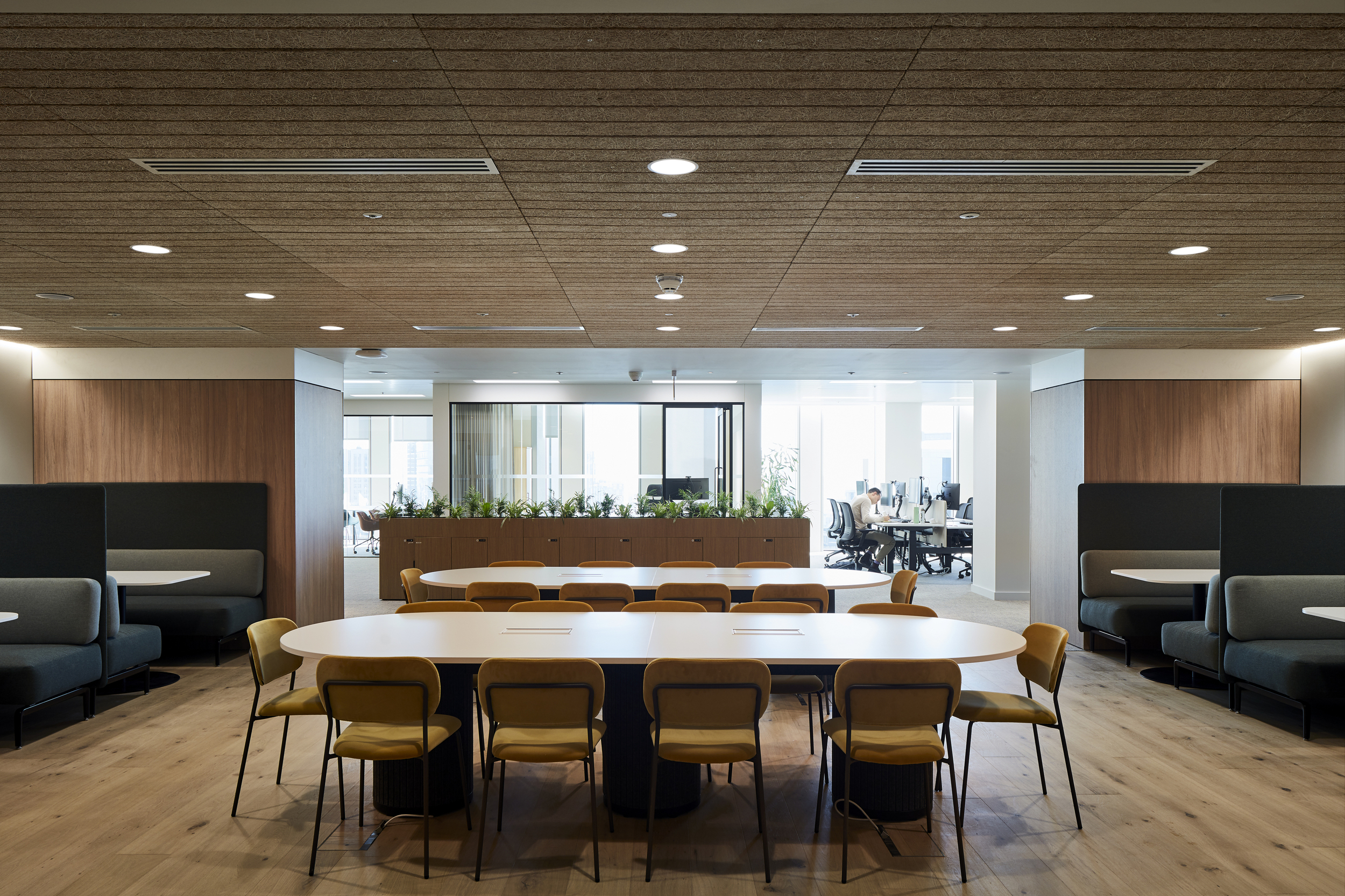 Shared workspace at McGill & Partners featuring Platfform-supplied meeting booths, long collaborative tables, and mustard yellow chairs.