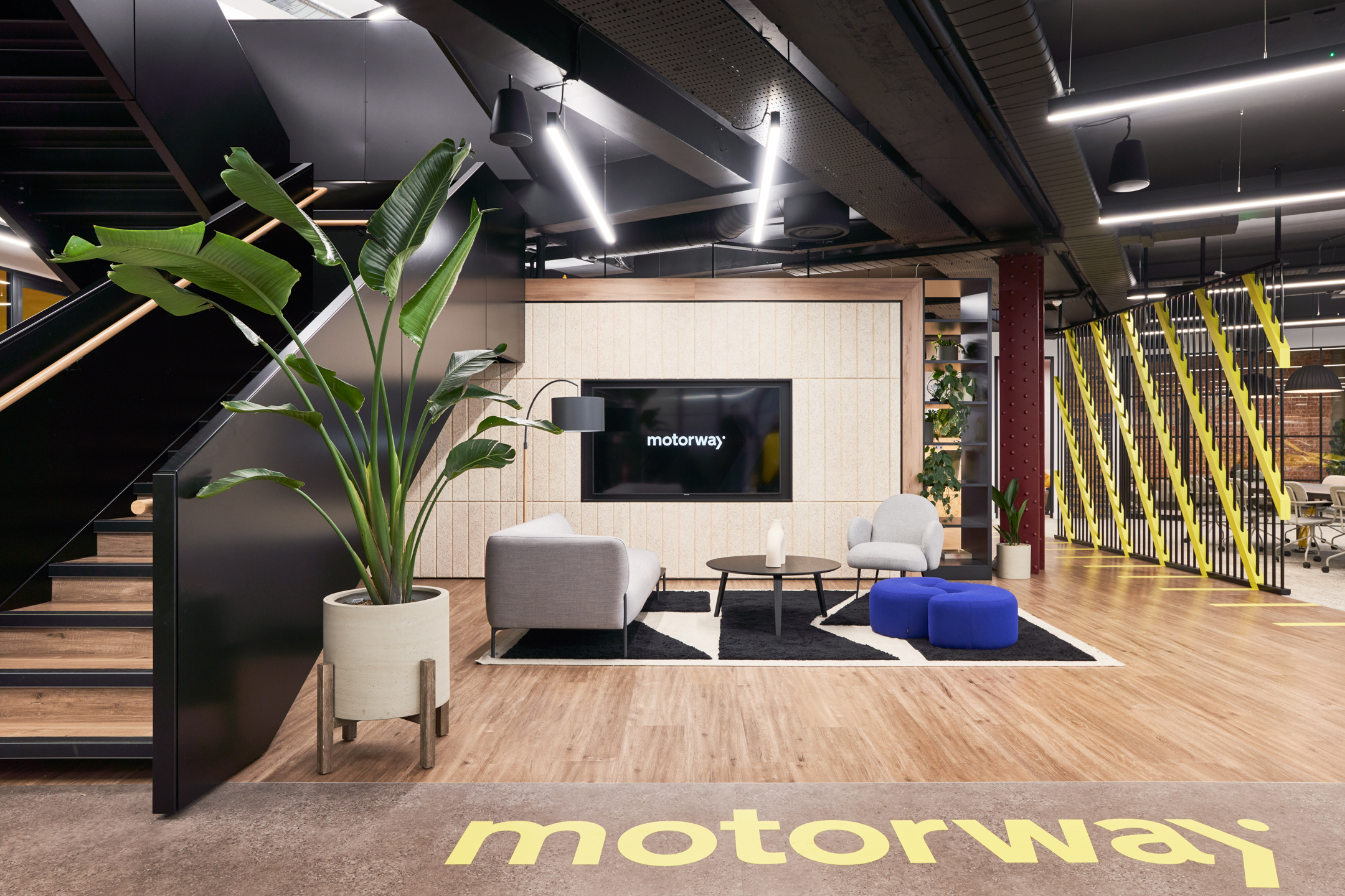 Reception lounge at Motorway’s workspace with contemporary furniture by Platfform, featuring soft seating and a large screen branded with the Motorway logo.
