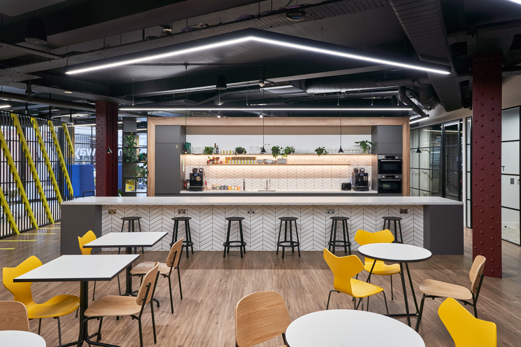 Teapoint at Motorway’s office featuring bespoke furniture by Platfform, including yellow dining chairs, café tables and a modern breakfast bar with high stools.