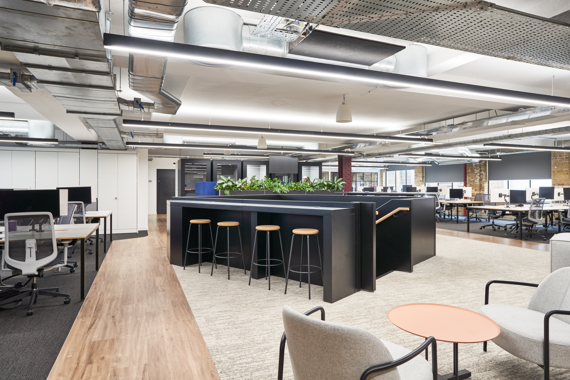 Open workspace at Motorway designed with sit-stand desks, collaborative bench seating, and soft breakout furniture by Platfform, set within an industrial-style interior.