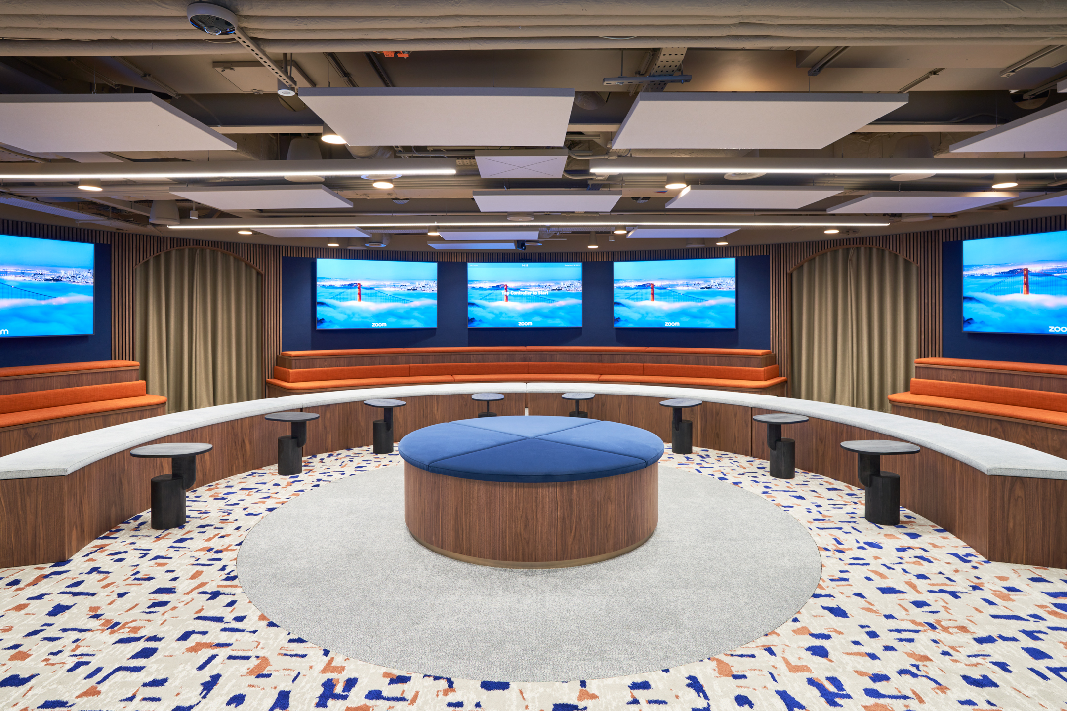Tiered seating and round upholstered furniture in a tech-enabled townhall space for Private Equity Fund, designed for presentations and collaboration.