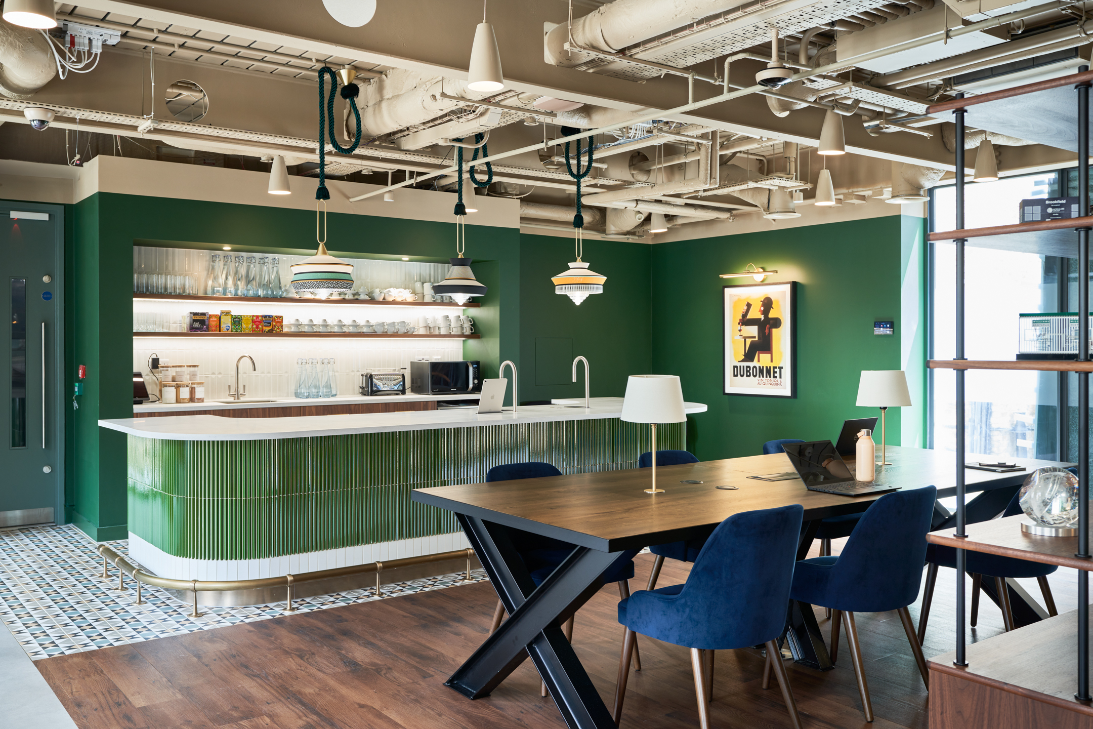 Eclectic kitchen and meeting zone at Private Equity Fund, featuring green tiled counter, pendant lighting, and plush blue seating for casual collaboration.