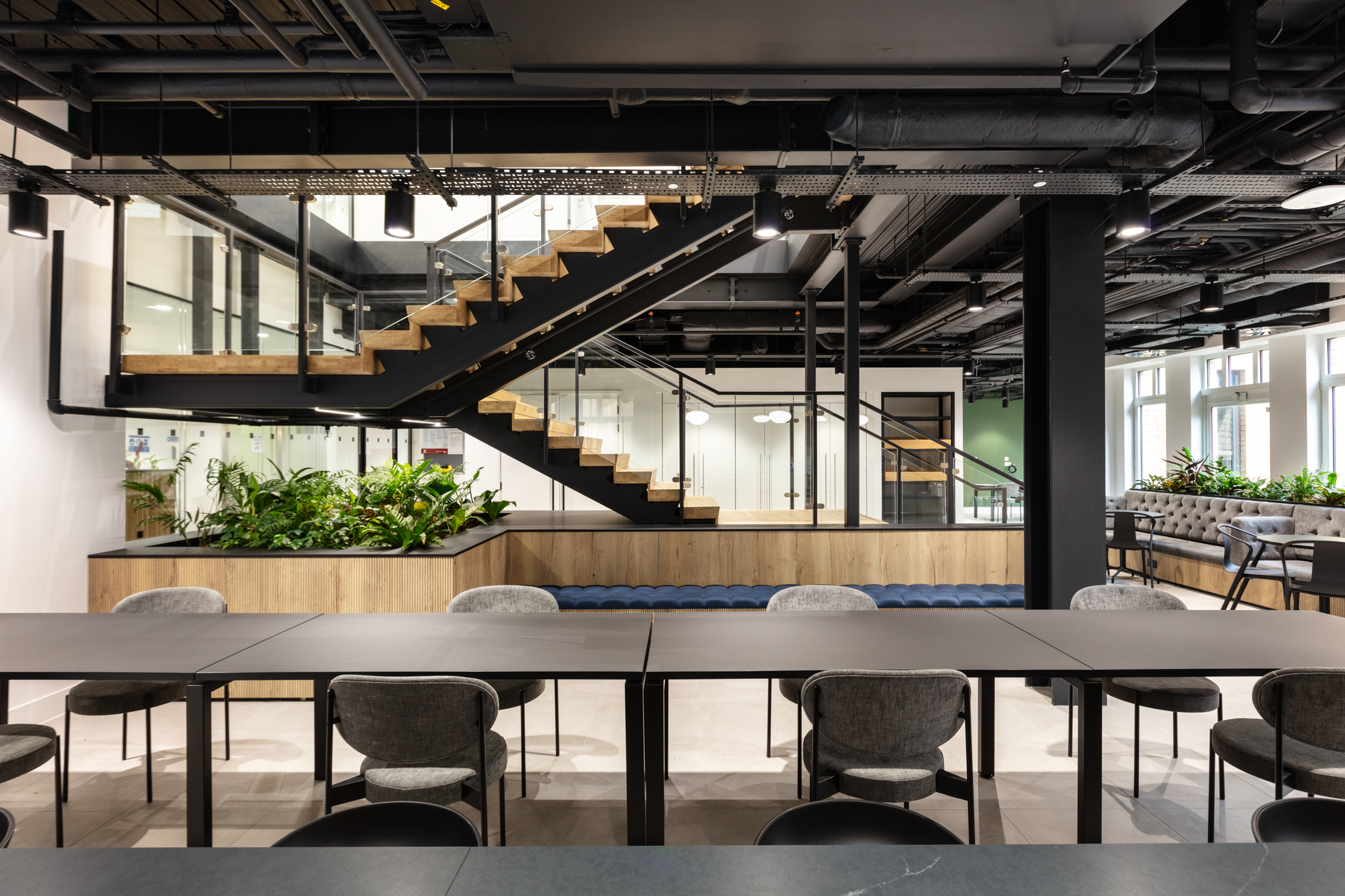 Workplace furniture by Platfform for Russell Reynolds Associates, including collaborative tables, soft seating and built-in planters beneath a feature stair.