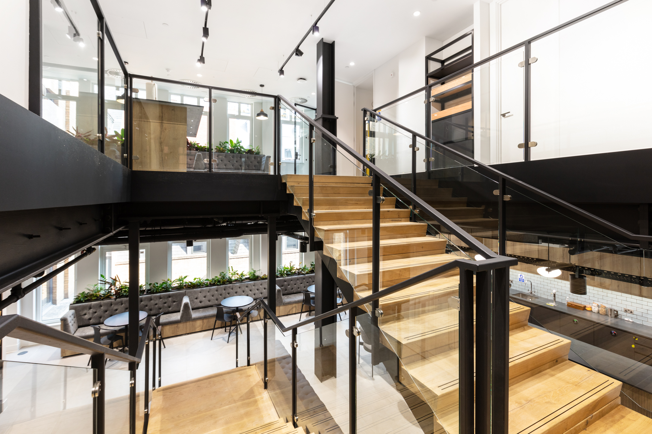 Bright stairwell space in Russell Reynolds Associates’ office, with layered views of lounge seating, planters and Platfform’s furniture across levels.