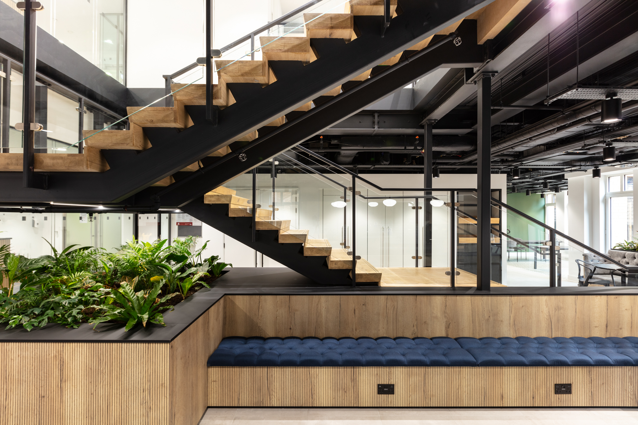 Russell Reynolds Associates staircase viewed from mid-level, showing furniture by Platfform with built-in seating, planters and lounge zones across floors.