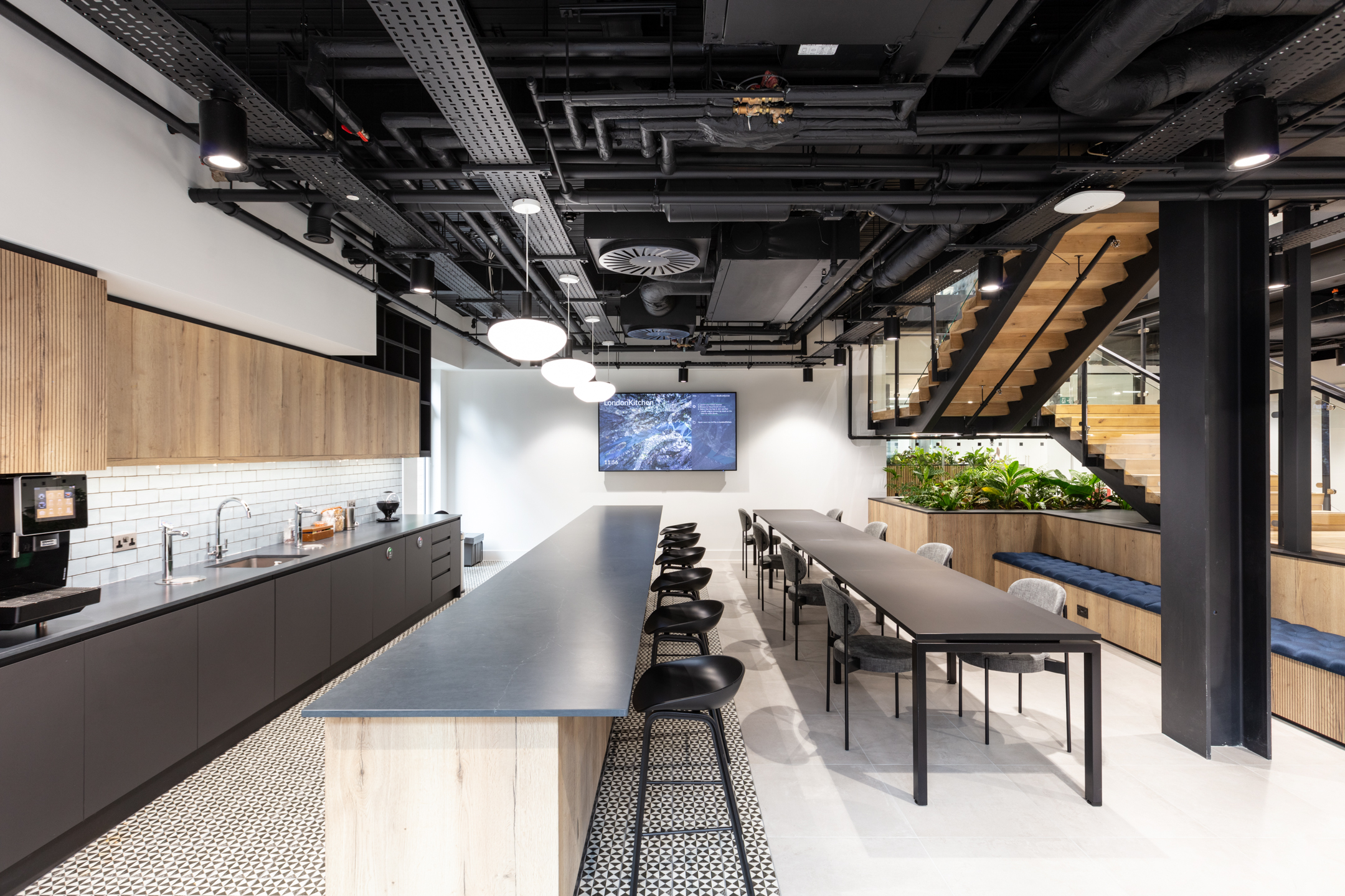 Open kitchen and shared workspace at Russell Reynolds Associates, with long tables, bar seating and furniture by Platfform designed for team connection.