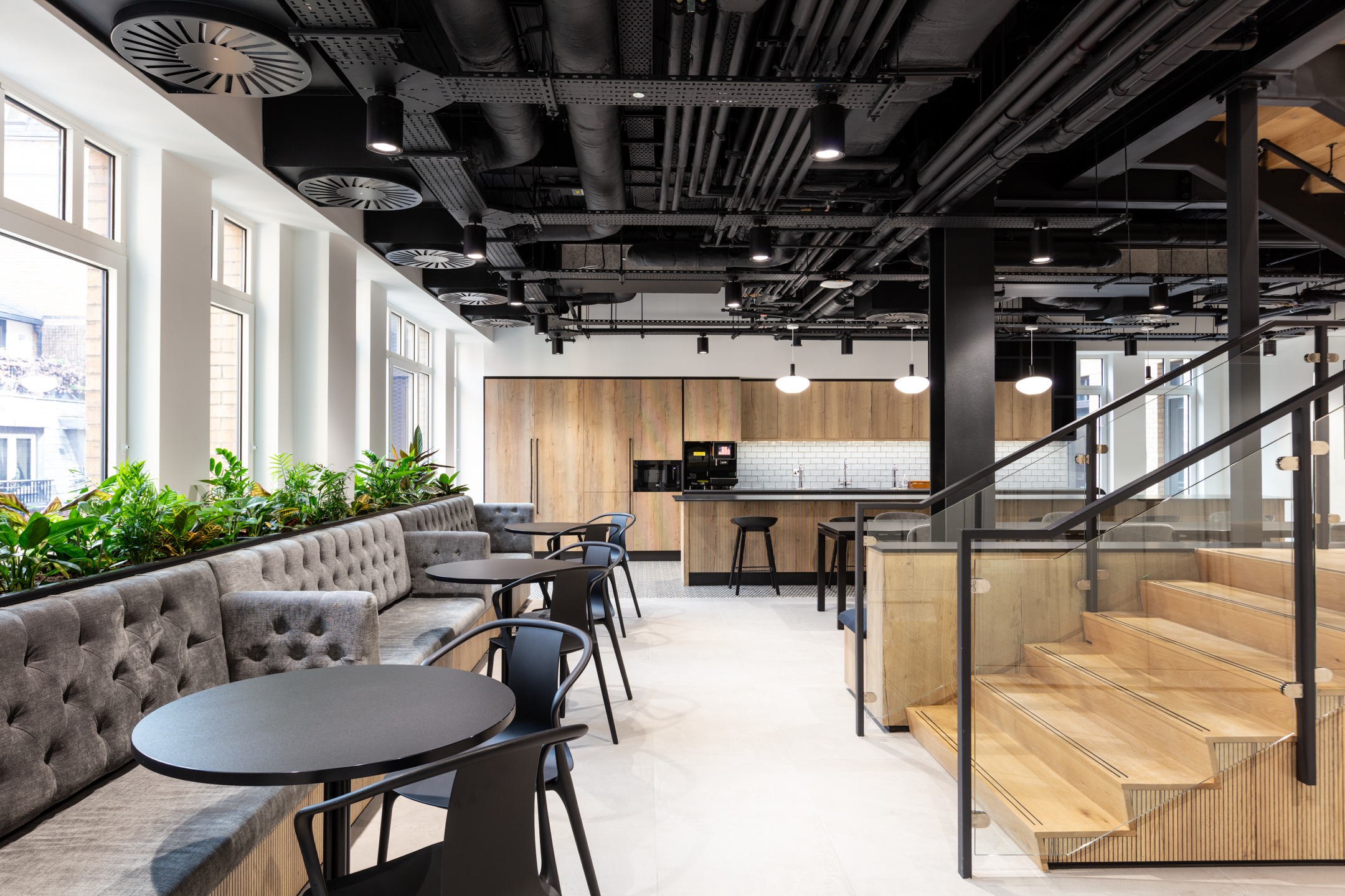 Casual seating and kitchen space for Russell Reynolds Associates, with buttoned banquettes, soft planting and round tables selected by Platfform.