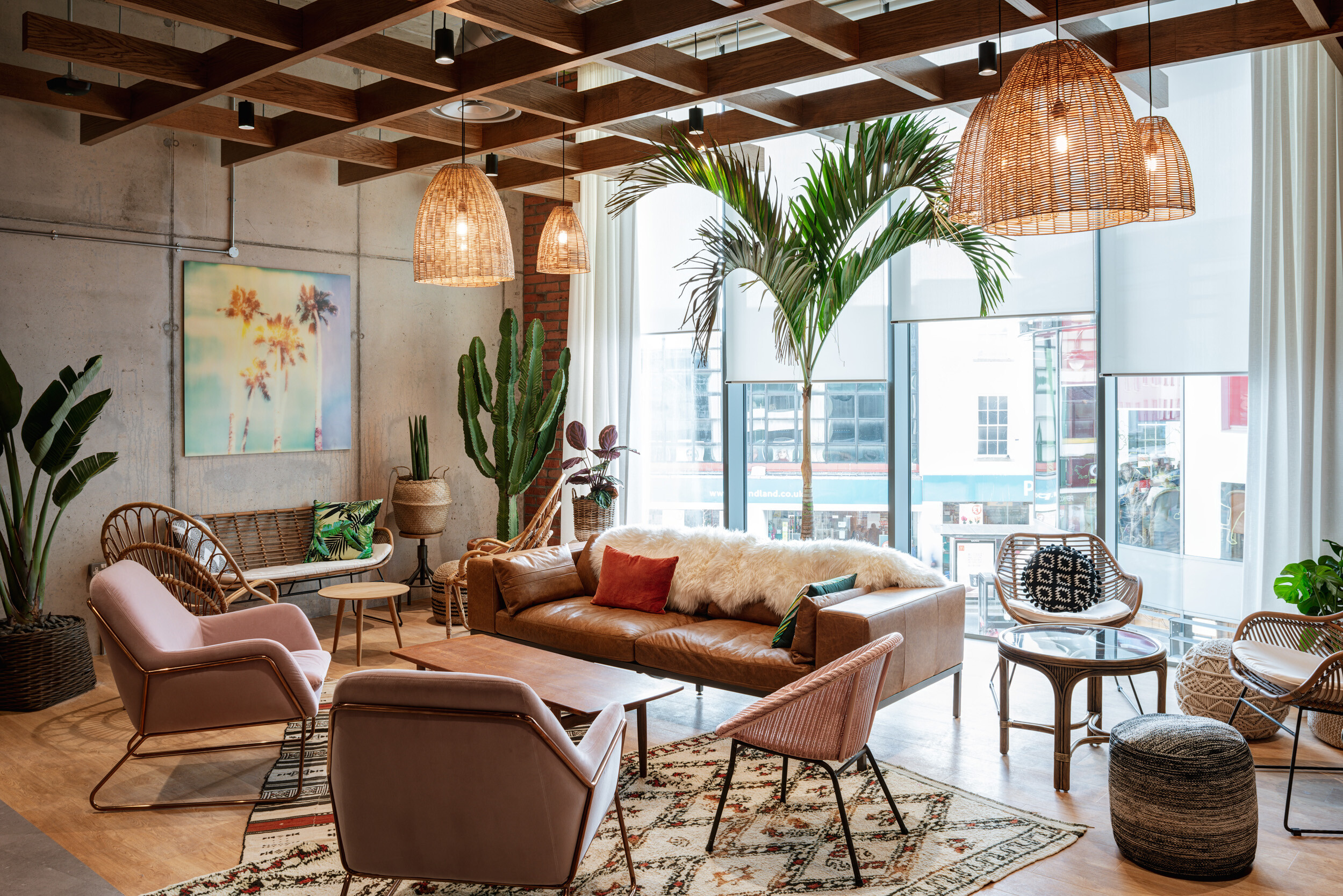 SLG’s Cheltenham lounge area featuring soft seating, woven accents and rattan pieces, furnished to reflect a relaxed, design-led brand culture.