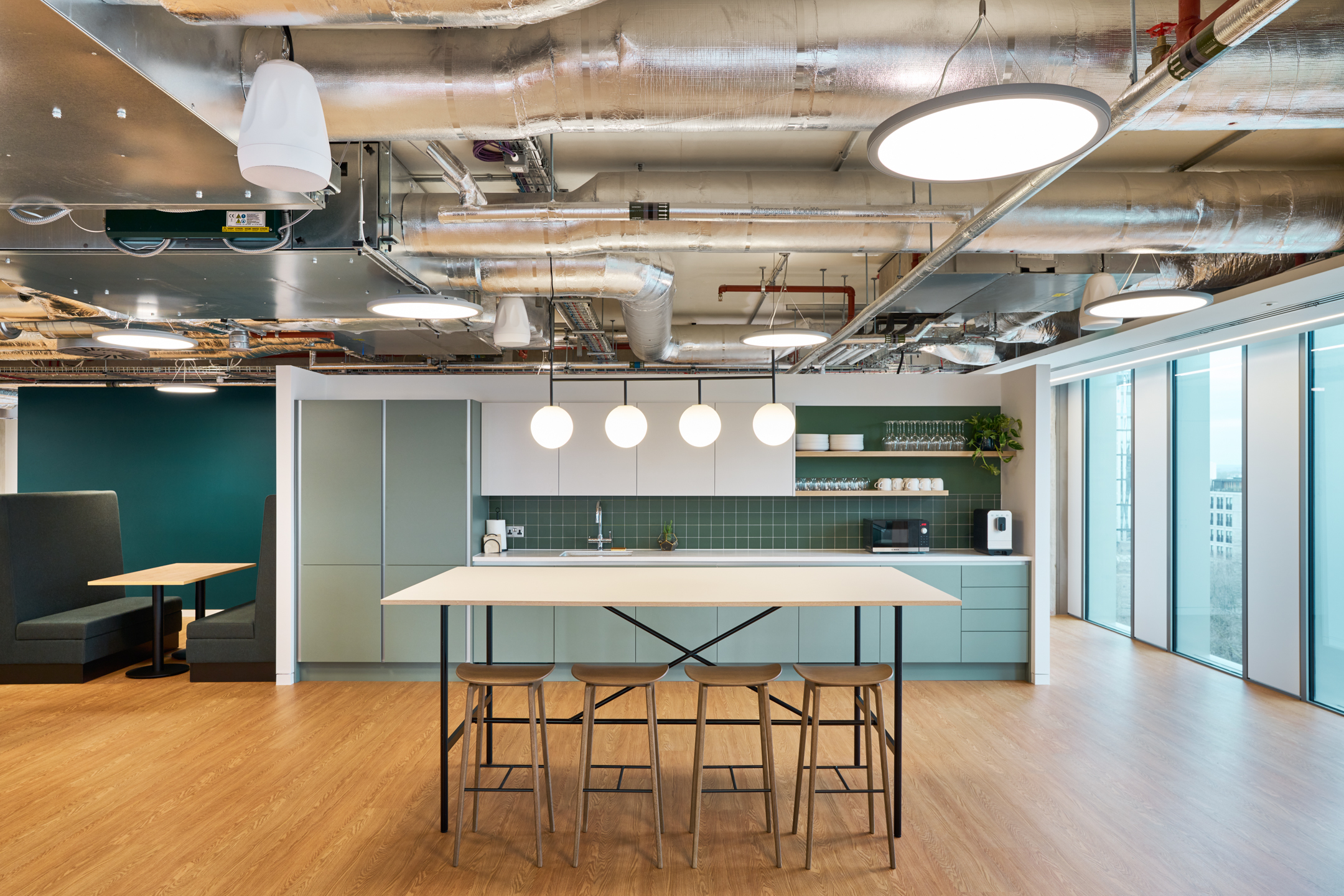 Salesloft kitchen area with mint green cabinetry, high stools and soft timber flooring, furnished by Platfform to complement the relaxed workspace style.