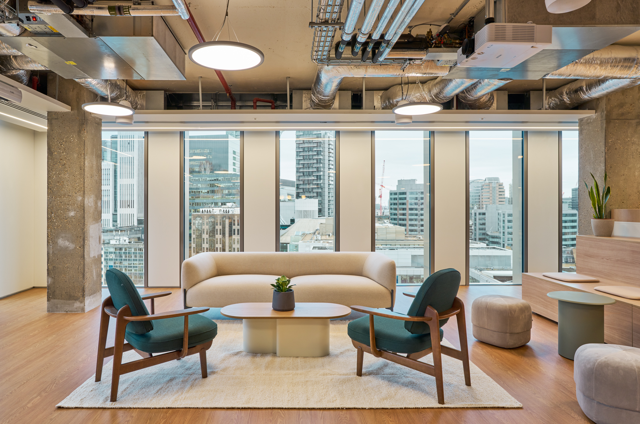 Salesloft lounge setup with soft cream sofa, teal armchairs and timber-framed furniture, supplied by Platfform to complete the relaxed workspace setting.