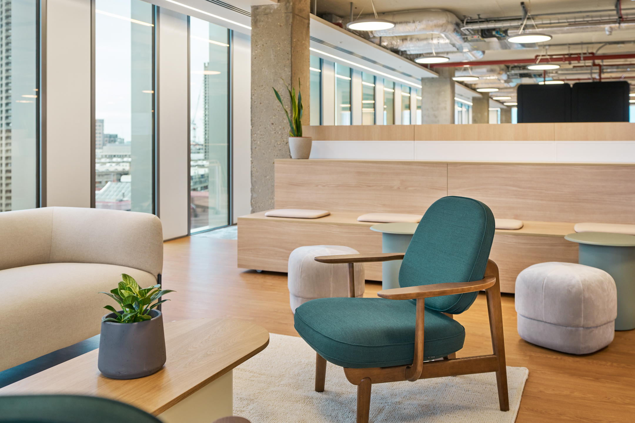 Close-up of Salesloft lounge furniture including green armchair, pale sofa and soft ottomans, selected by Platfform to support a calm, open layout.