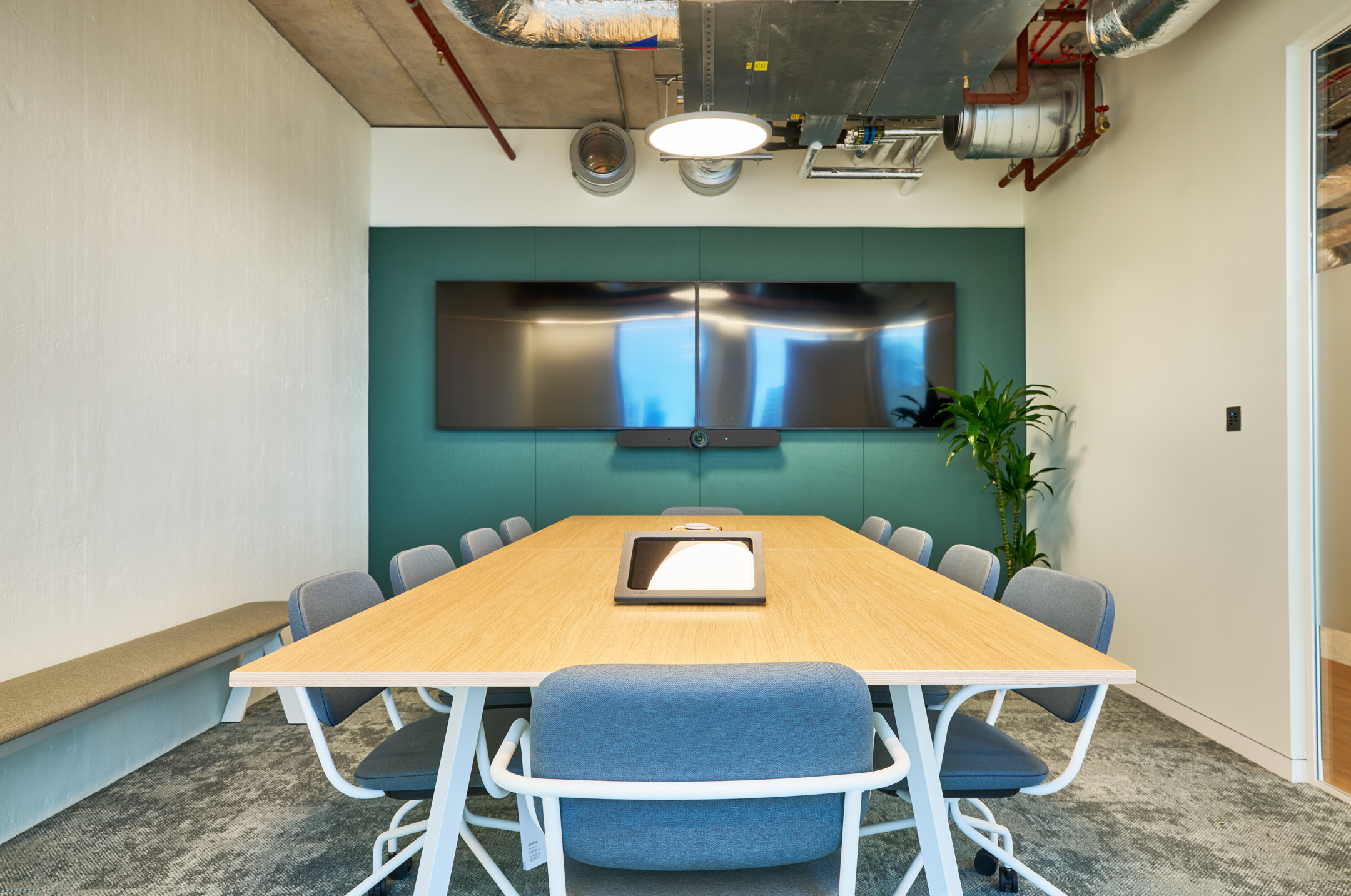 Salesloft meeting room with pale wood table, grey seating and dual screen setup, furnished by Platfform for a clean, focused collaborative environment.