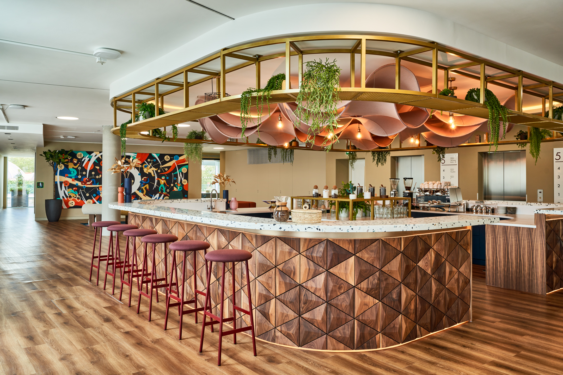 Bar-height stools and bespoke furniture by Platfform at the Publicis Sapient office teapoint, with timber textures, terrazzo surfaces and hanging greenery.