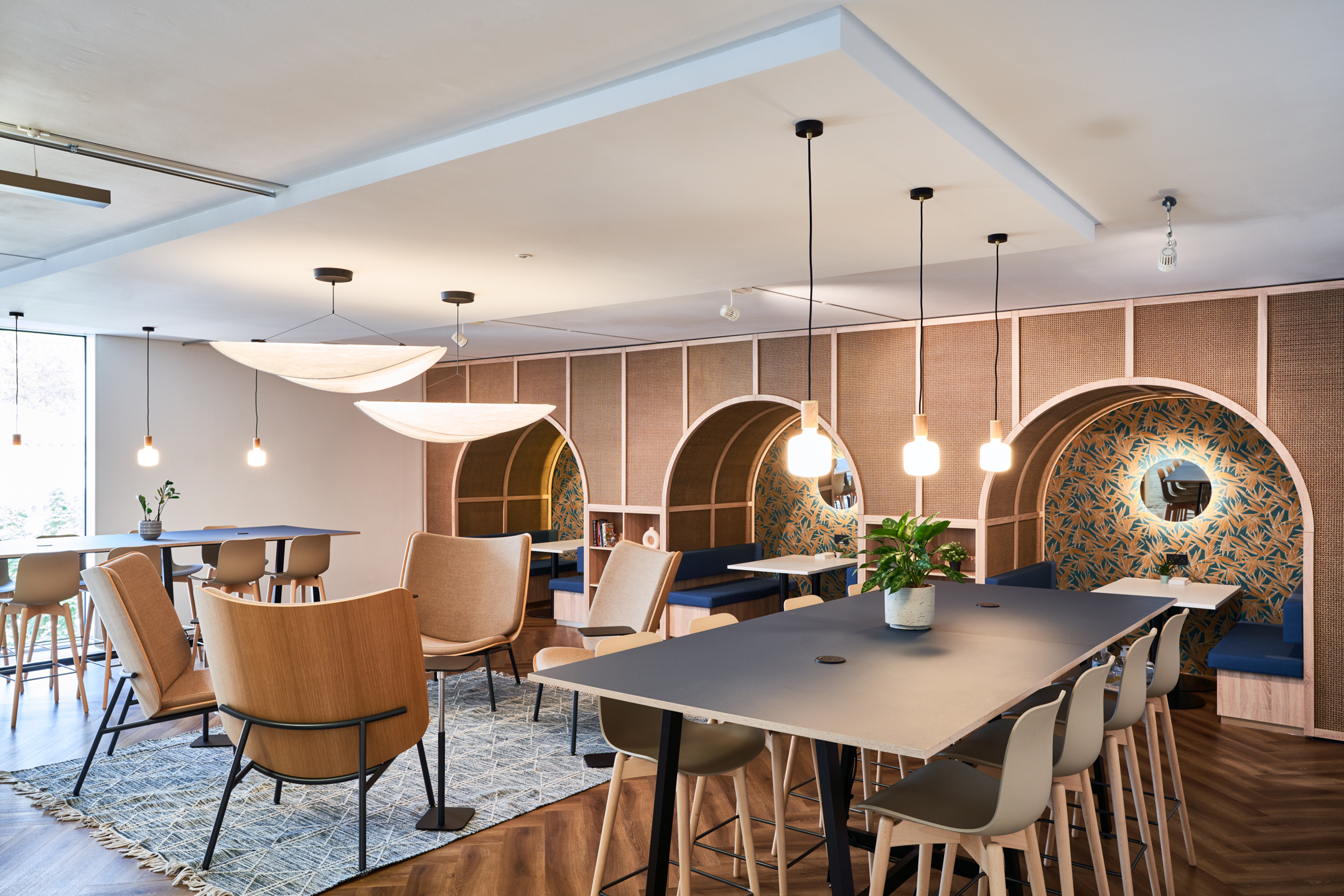 Furnished breakout space at Publicis Sapient with layered seating zones by Platfform, including high tables, lounge chairs and curved booth seating set against rattan panelling.