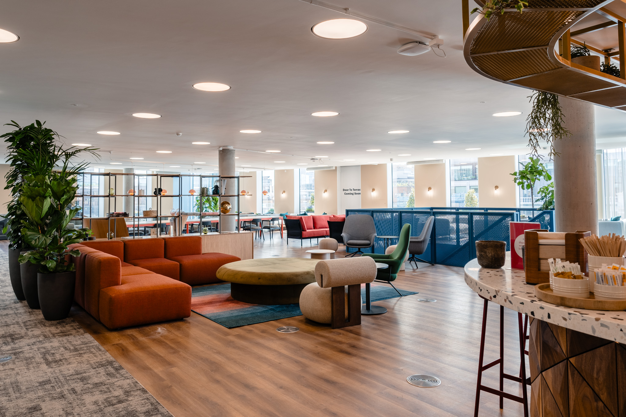 Flexible lounge zone at Publicis Sapient, with furniture by Platfform including rust-coloured seating, sculptural armchairs and layered soft furnishings for a relaxed, informal atmosphere.