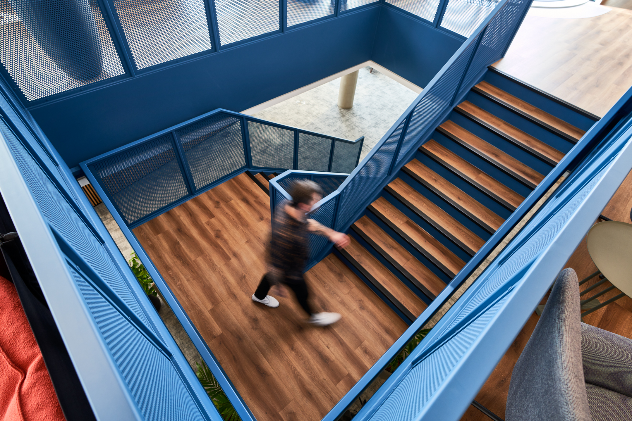 Staircase at Publicis Sapient with bold blue metal balustrades and warm timber flooring, connecting the office’s collaborative work zones furnished by Platfform.